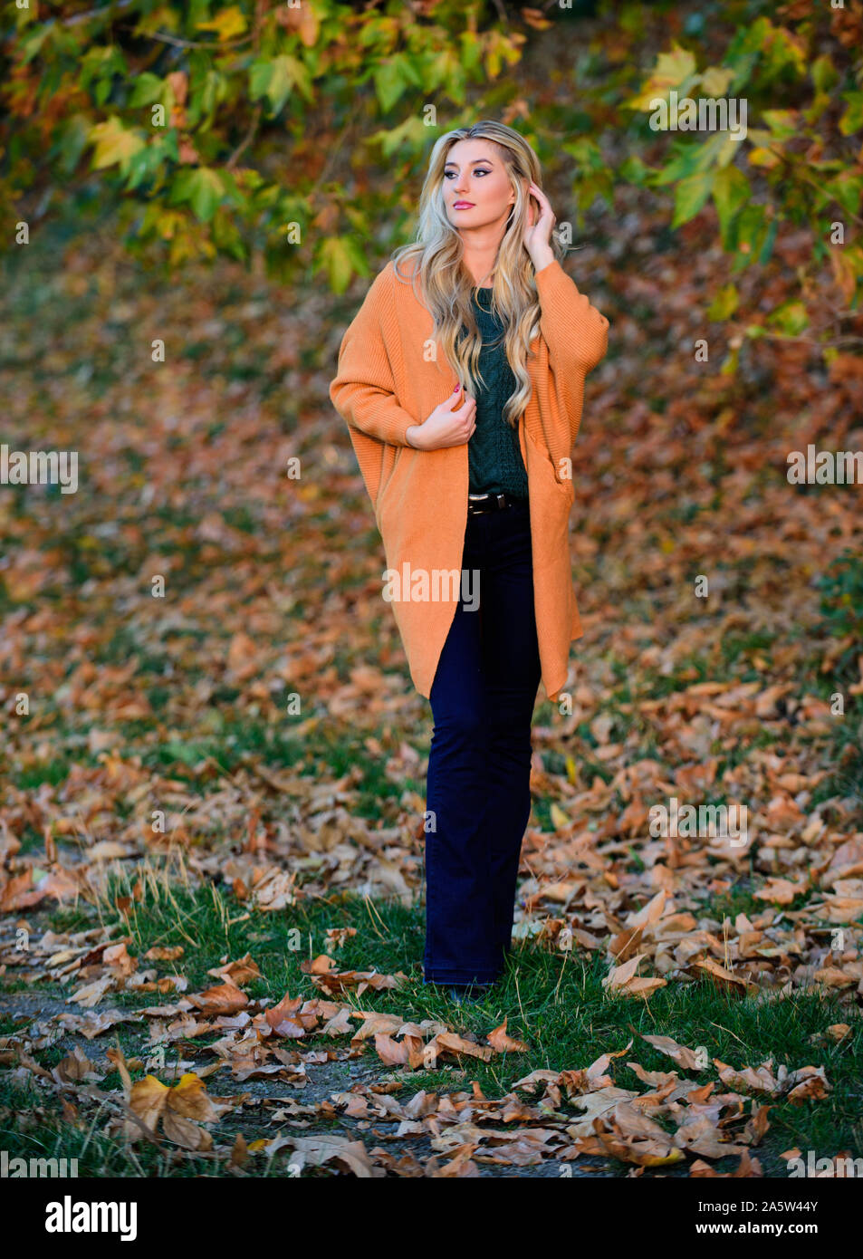 Femme à pied. La lumière au coucher du soleil Des vêtements pour tous les  jours. Adorable petite fille blonde posing in outfit chaleureux et cosy de  l'automne nature fond flou. Tenues décontractées