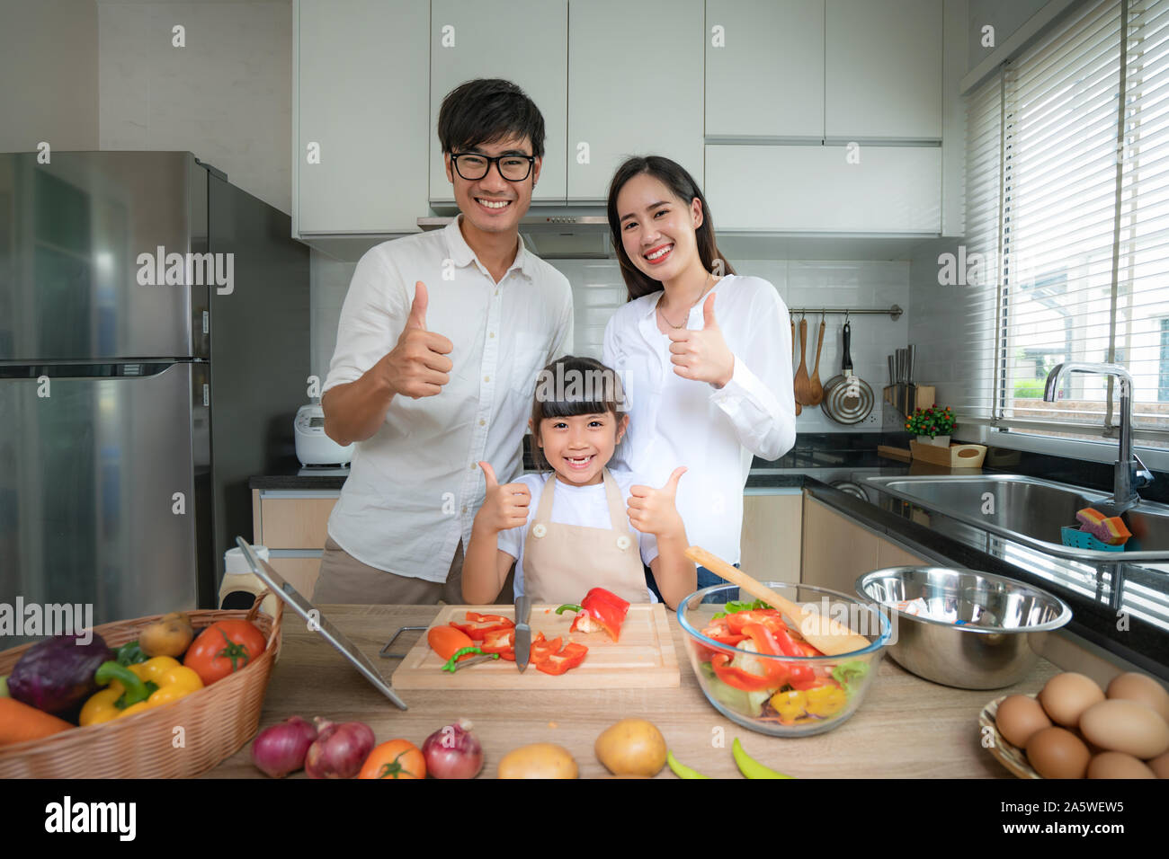 Asian family avec père, mère et fille salade de légumes râpés et bruit jusqu'alors que la famille était la cuisson dans la cuisine à la maison. La vie de famille l Banque D'Images