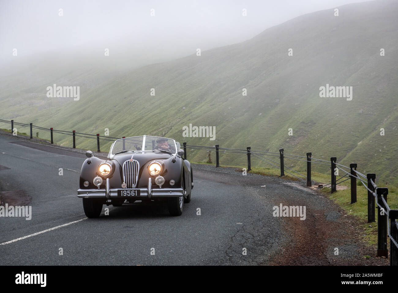 Un homme conduit sa Jaguar XK120 classique autour de la campagne de backroads Hawes, Yorkshire, UK Banque D'Images