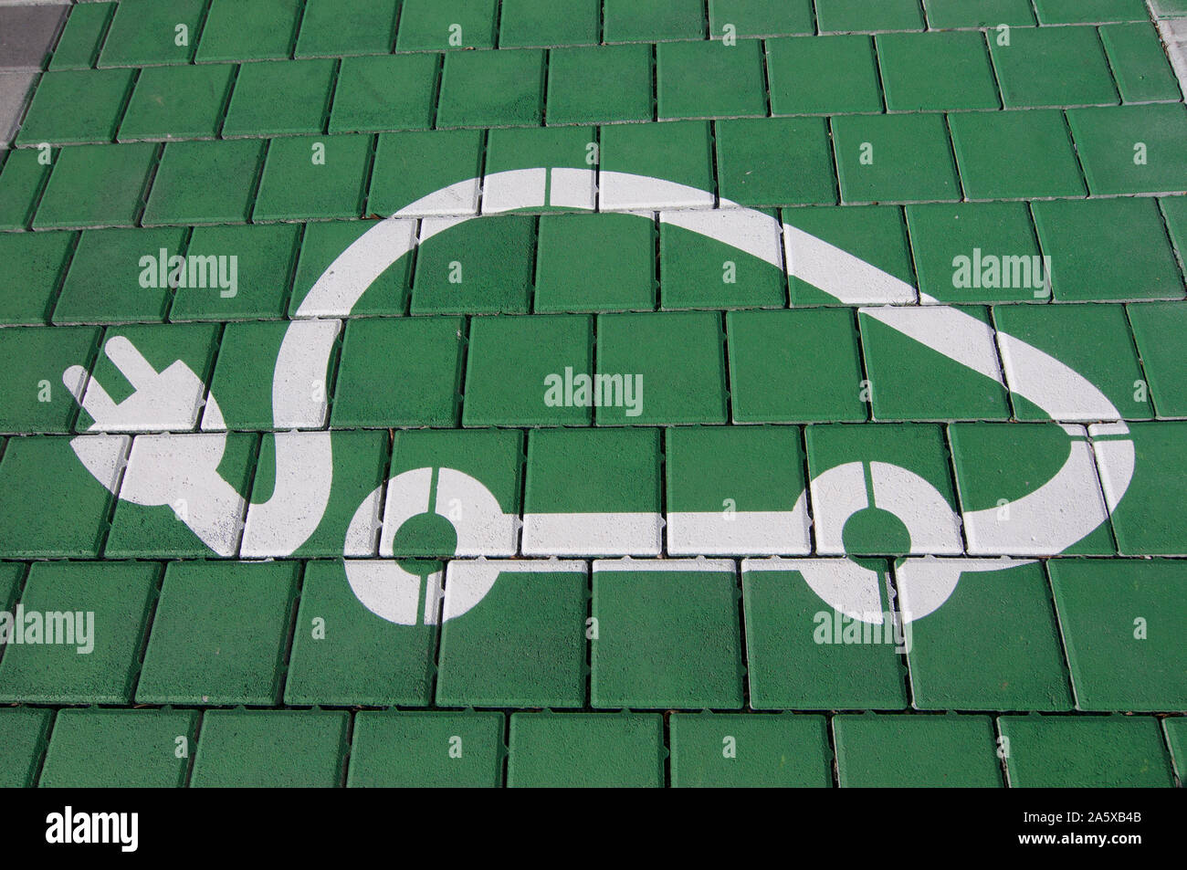 Close up photo d'une station de recharge de véhicules électriques symbole sur un fond vert, capturé à Lugano (Tessin) - Suisse Banque D'Images