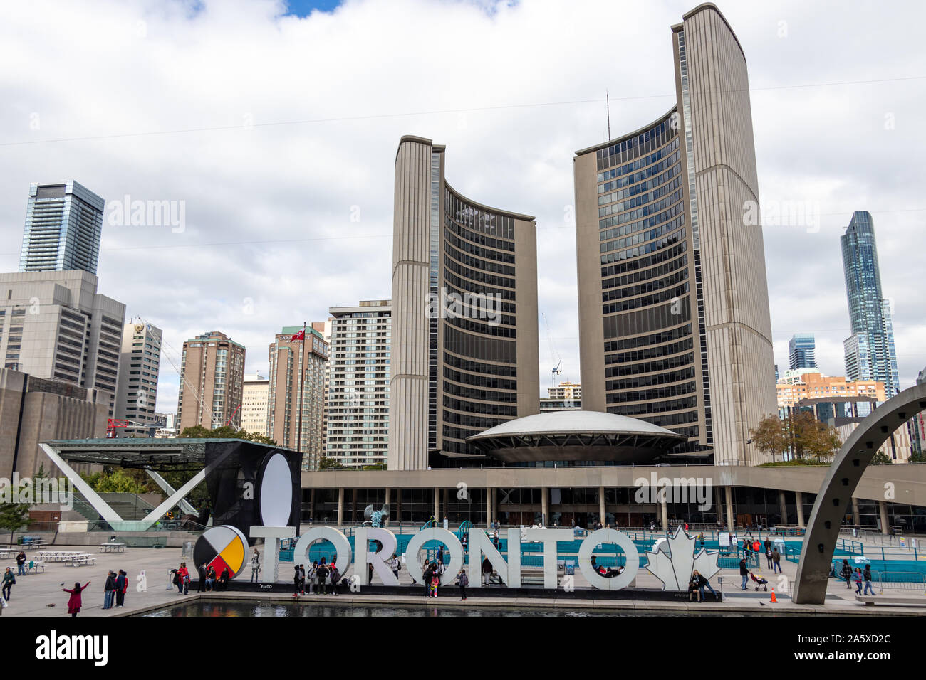 L'hôtel de ville de Toronto et Toronto signent Nathan Philips Square tandis que les touristes se mêlent autour d'un après-midi animé. Banque D'Images