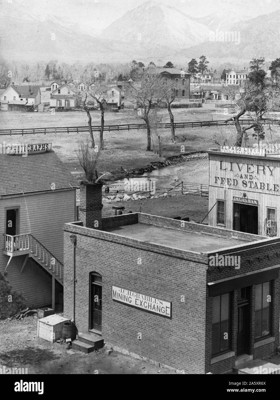 La photographie montre trois bâtiments avec des signes lecture : l'exploitation minière Grabill change, des photographies, et El Paso Livery ; river et maisons en milieu-sol, montagnes en arrière-plan. Banque D'Images