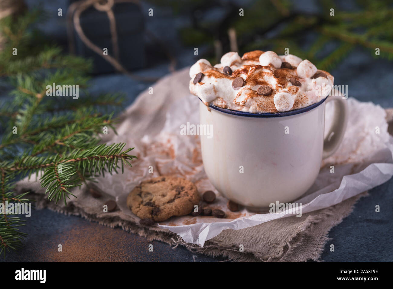 Luxurious chocolat chaud avec de la crème chantilly et des morceaux de guimauves et chocolat, dans un mug blanc sur fond bleu. Banque D'Images