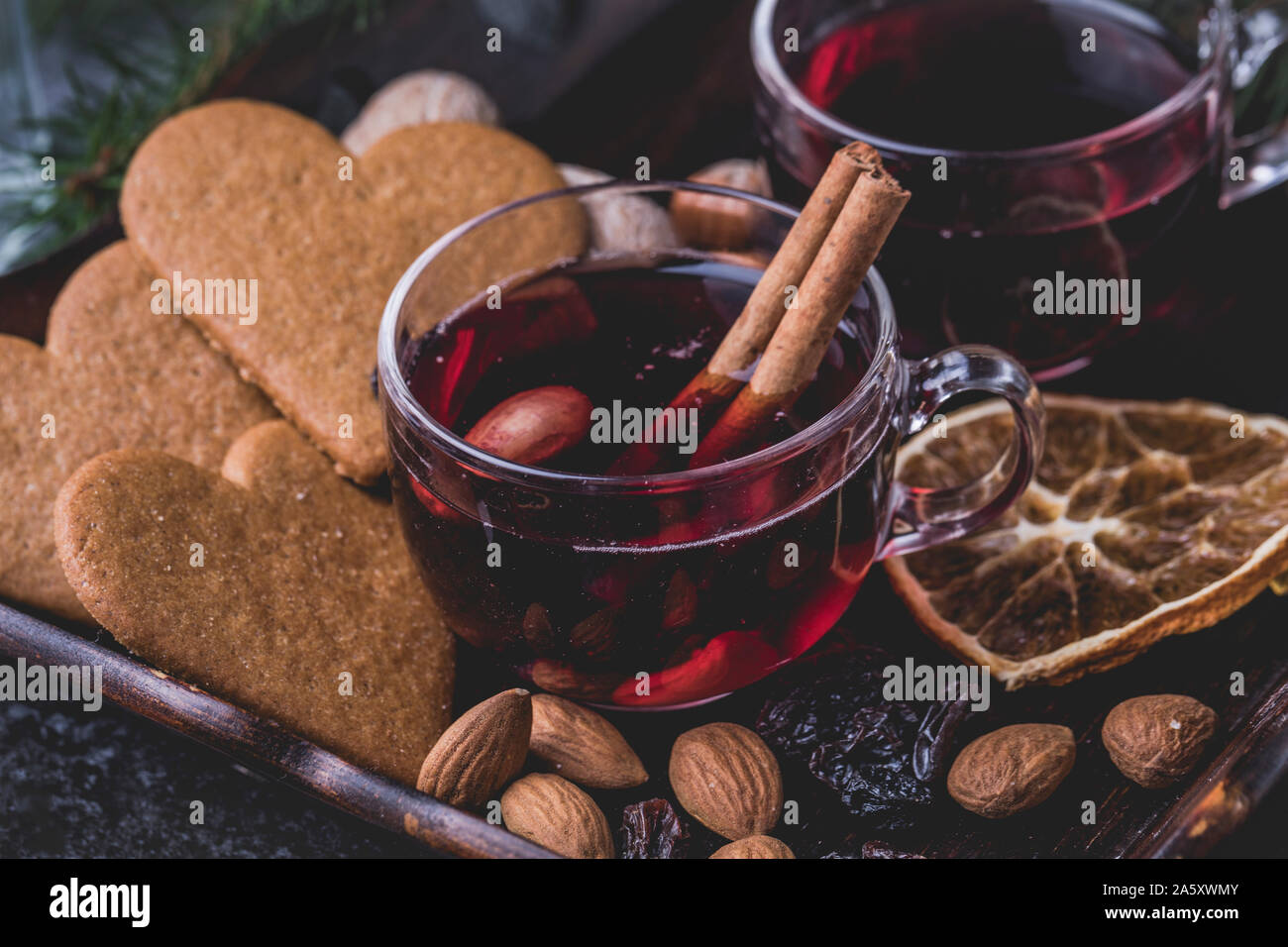 Vin chaud avec des bâtons de cannelle. Les verres sont sur un plateau en bois foncé en forme de coeur entouré de gingerbread cookies traditionnels suédois, raisins, al Banque D'Images