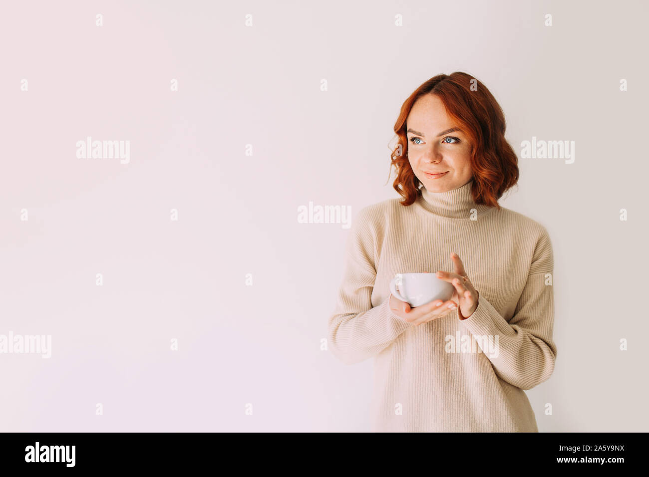 Portrait de style belle femme aux cheveux rouges à boire du café dans une tasse blanche, portant un chandail. Banque D'Images