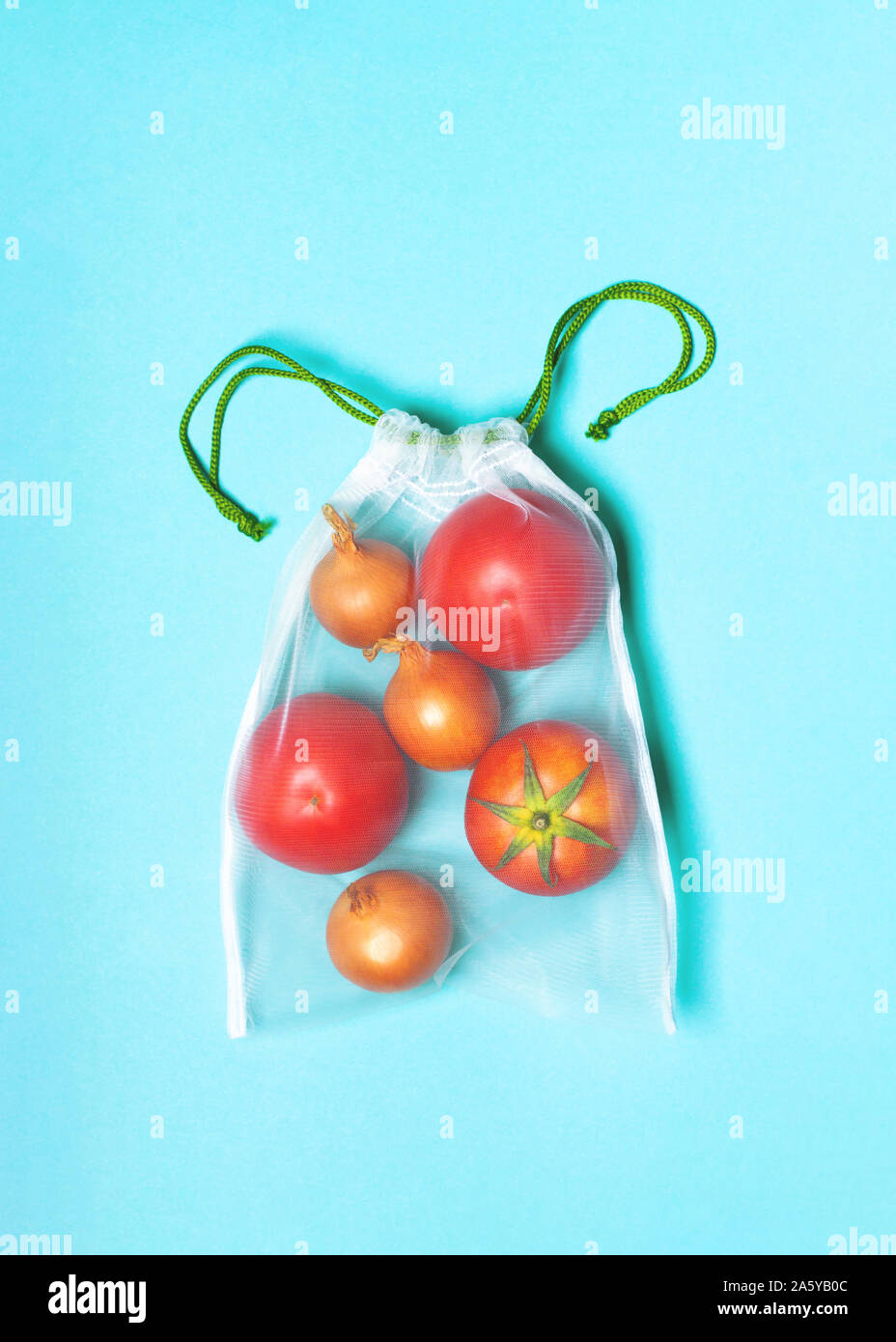 Or l'oignon et les tomates biologiques dans l'eco sac sur un fond bleu. Concept zéro déchet, plastique, l'éco-friendly shopping, végétalien Banque D'Images