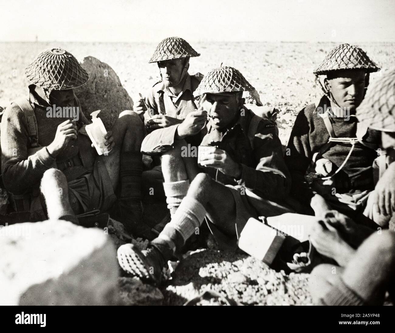 Les hommes de la division néo-zélandaise dans le désert occidental prendre du temps pour le déjeuner. Dans le centre, une cuillère à la bouche, est le sous-lieutenant Charles Kazlett Upham, a attribué la V.C. pour ses exploits remarquables au cours des combats en Crète 1942 Banque D'Images