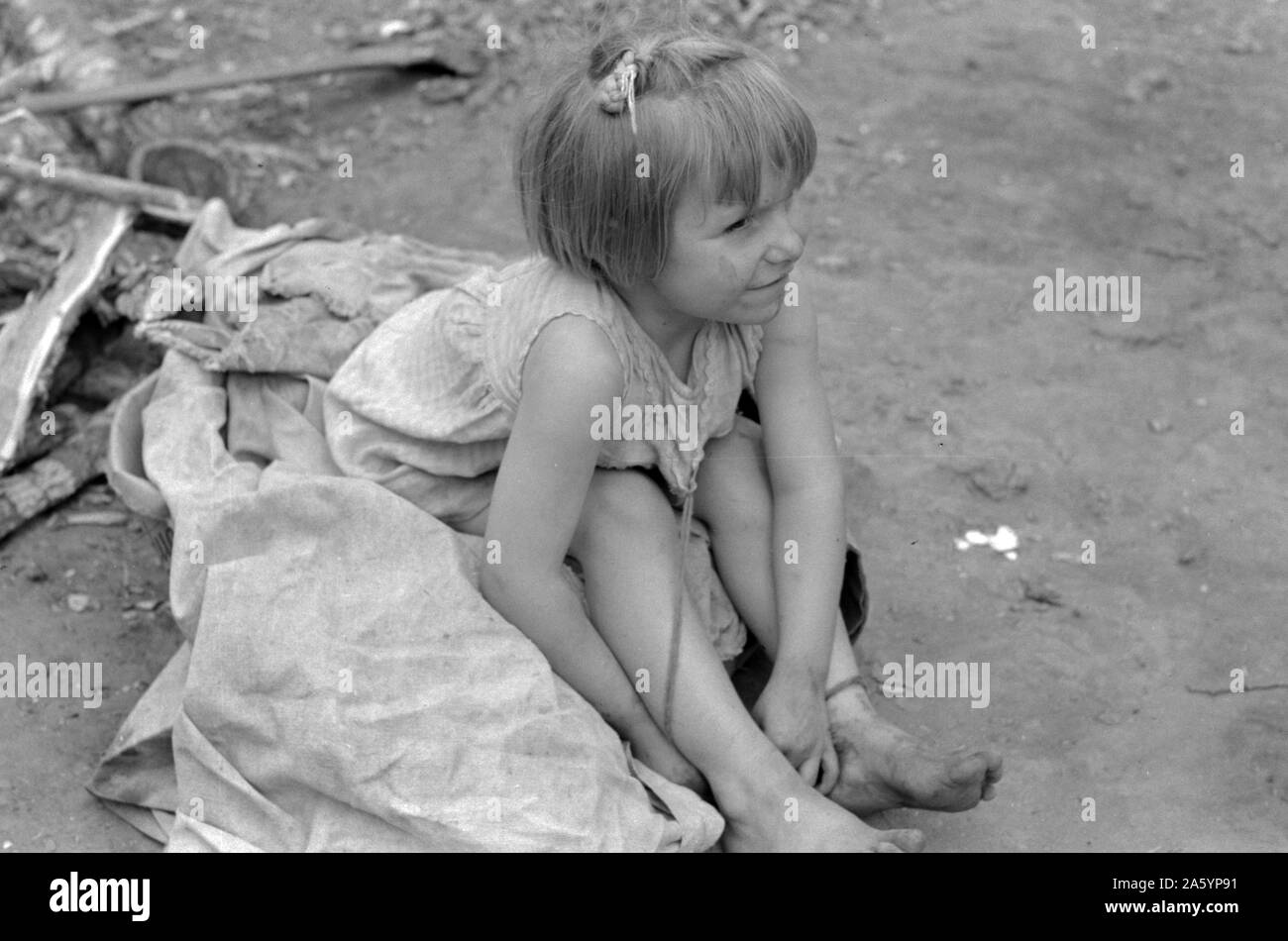 Enfant de travailleur migrant blanc assis sur des sacs de coton près de Harlingen, Texas par Russell Lee, 1903-1986, en date du 19390101. Banque D'Images