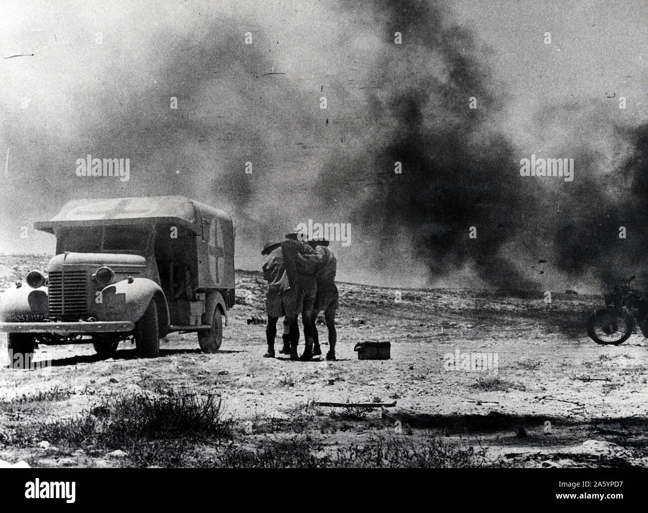 Tirage photographique d'une attaque de l'ennemi sur un convoi du désert d'ambulance. Deux soldats du Royal Army Medical Corps transporte un autre soldat d'une croix rouge, ambulance. Datée 1941 Banque D'Images