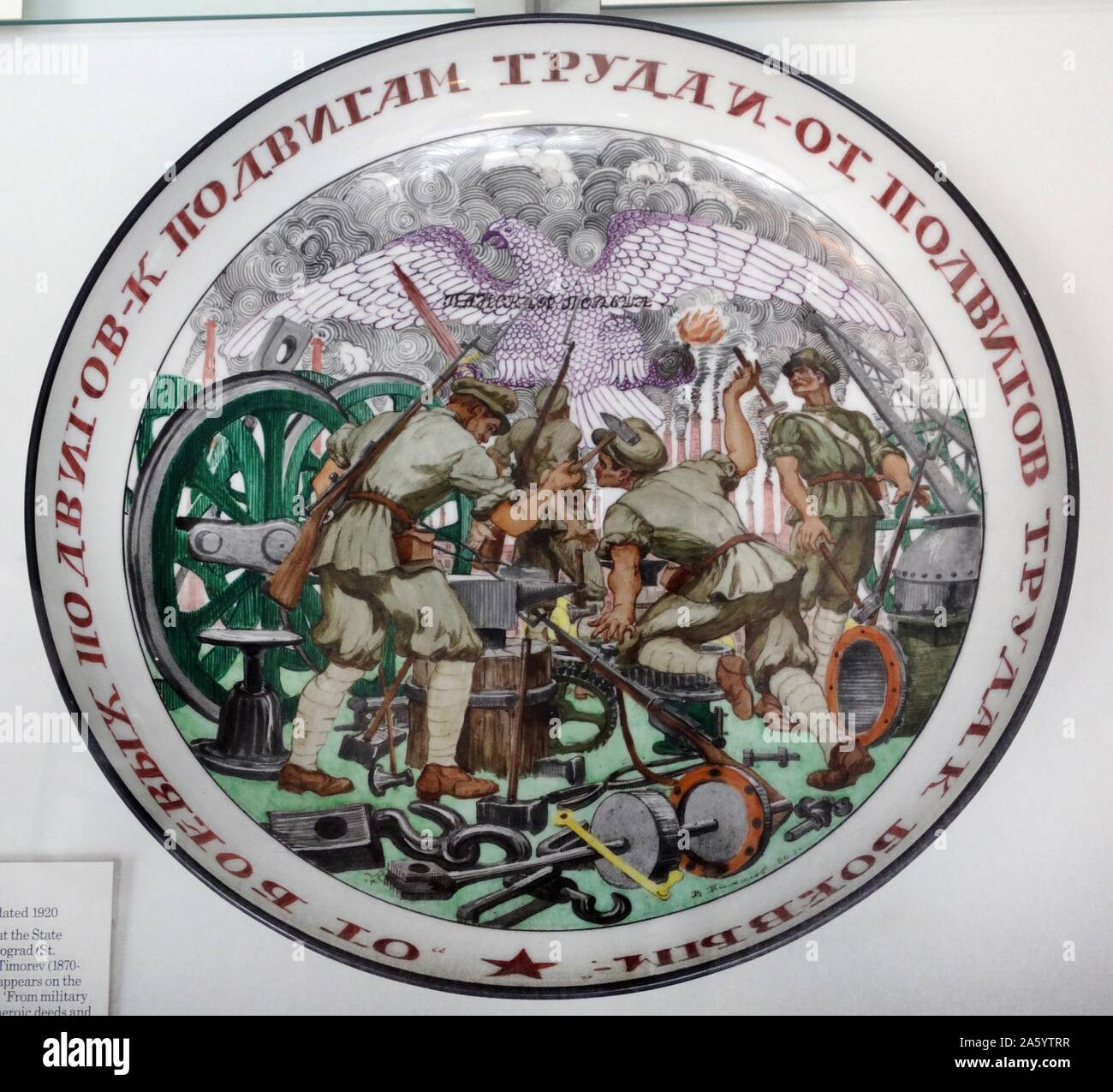 Plat en porcelaine ; russe, signé et daté 1920, conçu et peint à l'état d'usine de porcelaine, Petrograd (St. Petersburg), par Vasilii Timorev (1870-1942), dont la signature apparaît sur l'avant. Le slogan se lit comme suit : "des hauts faits militaires à la main-d'actes héroïques et de hauts faits du travail de hauts faits militaires' avec un aigle et les mots "la Pologne des riches propriétaires se référant à la guerre contre la Pologne à la fin de la guerre civile russe. Banque D'Images