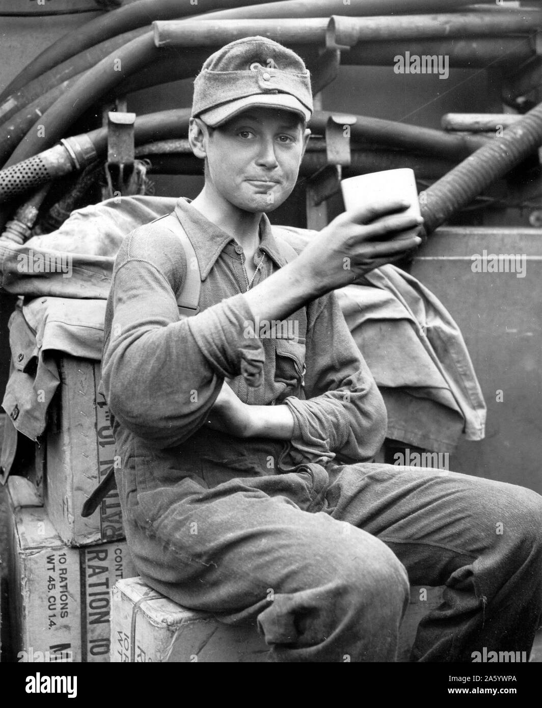 Photographie d'un jeune Allemand capturés et savourer une tasse de café à bord d'un des garde-côtes des États-Unis côte normande. En date du 1944. Banque D'Images