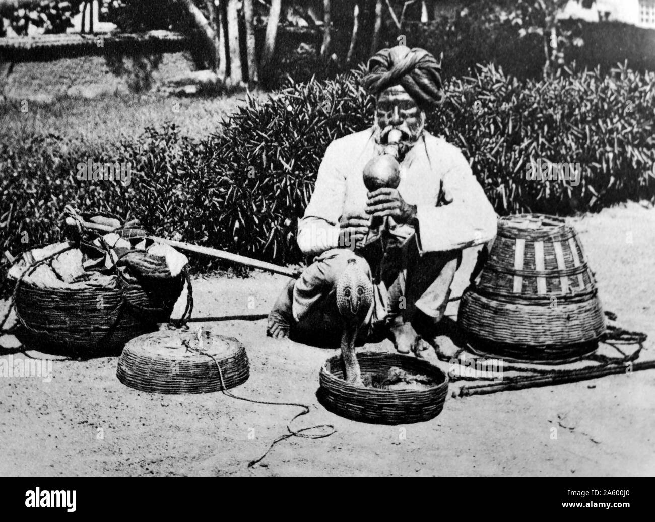 Charmeur de serpent indien avec flûte leurre d'un cobra à partir d'un panier 1925 Banque D'Images