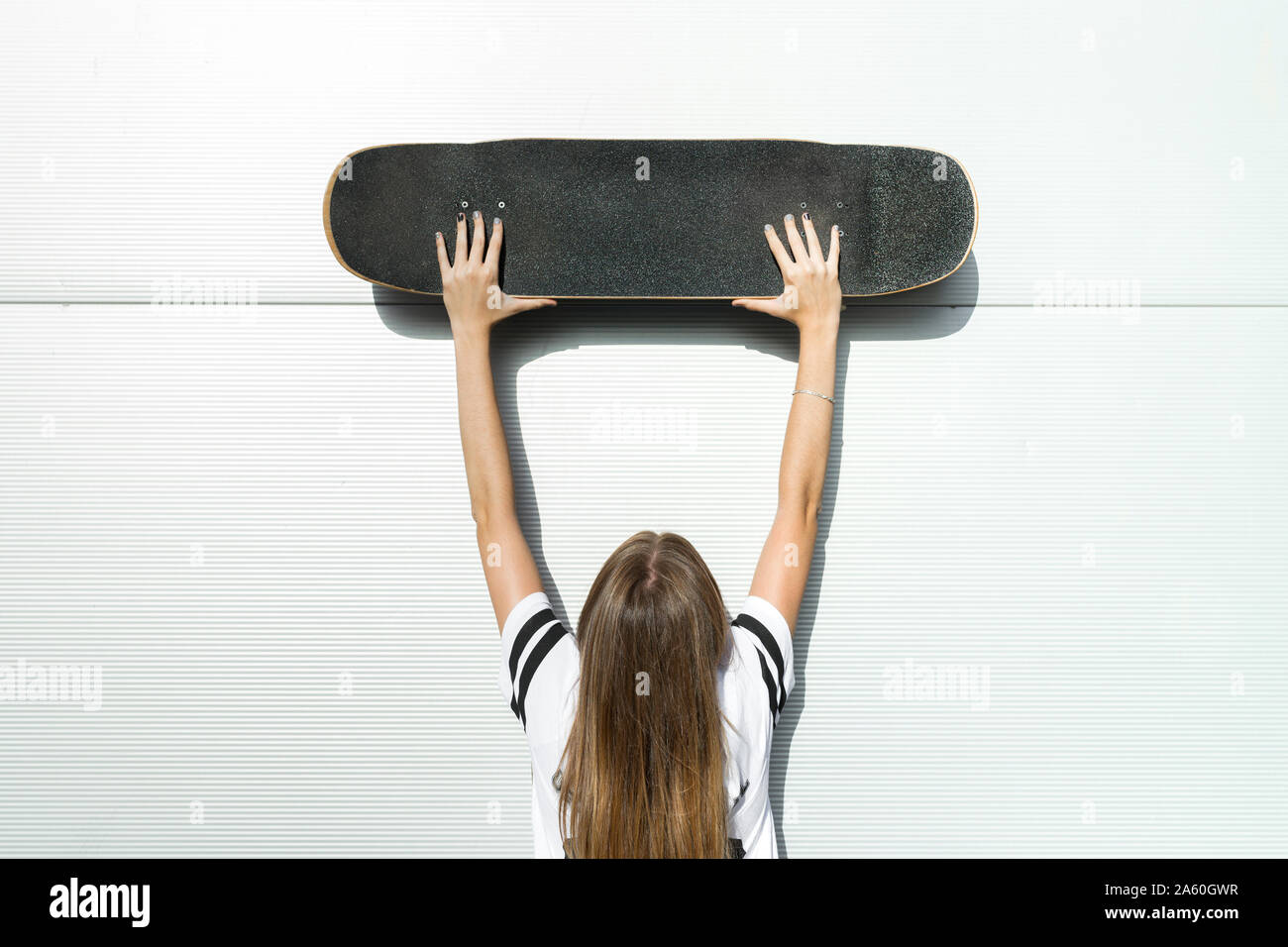 Vue arrière de la jeune femme, skaptboard en altitude Banque D'Images