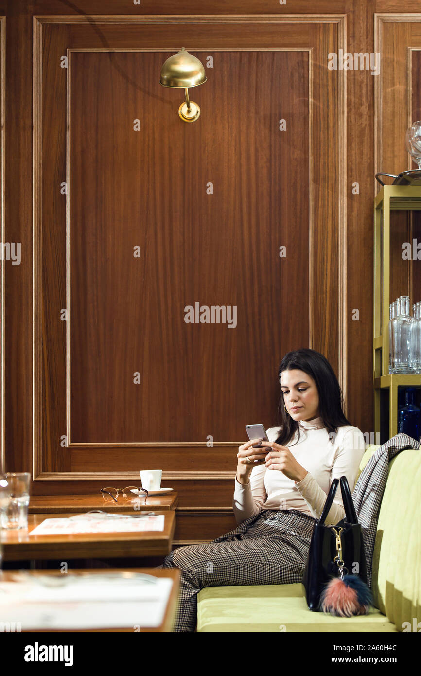 Businesswoman using cell phone in a restaurant Banque D'Images