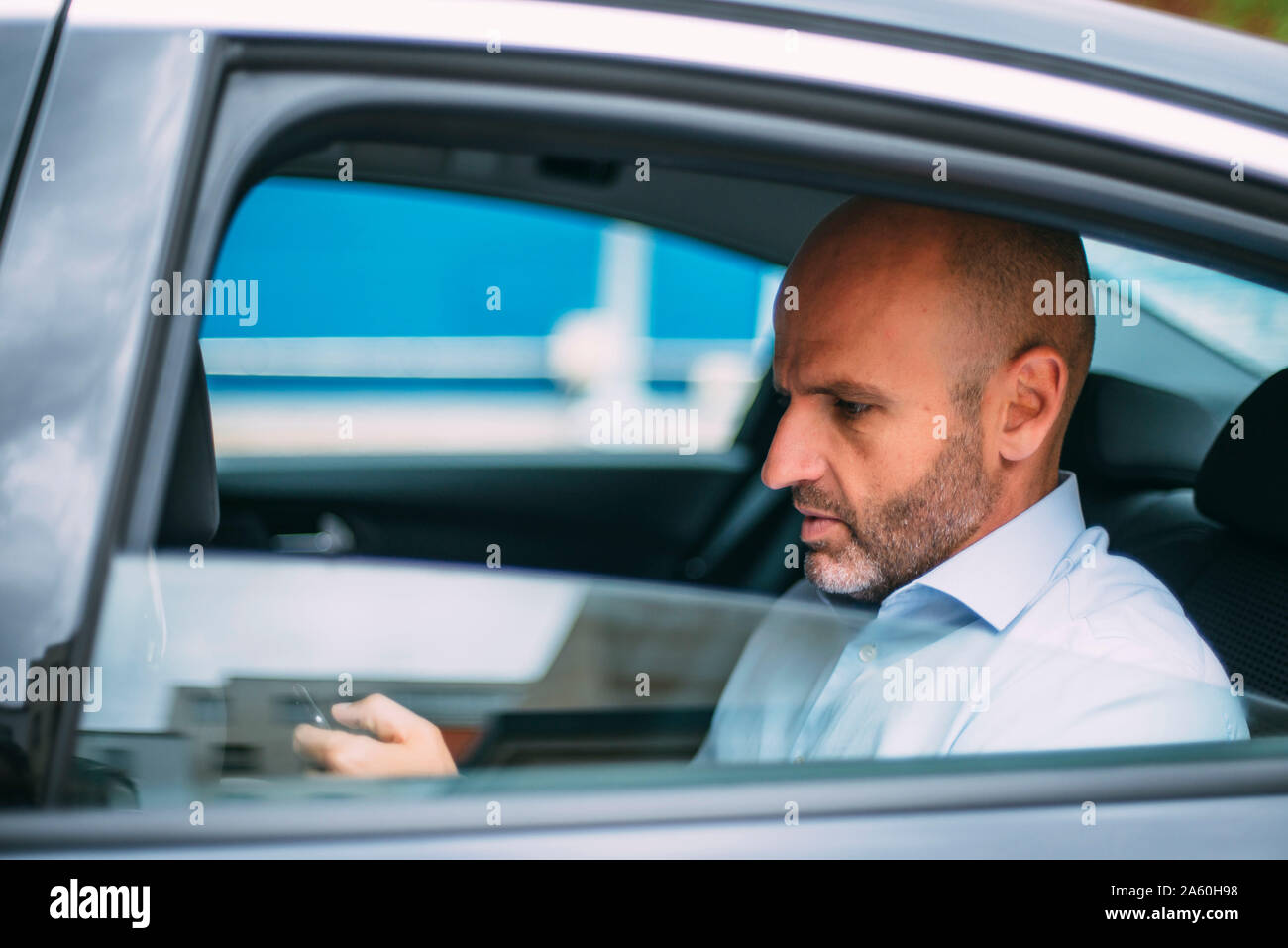 Businessman assis sur un siège arrière de la voiture using smartphone Banque D'Images