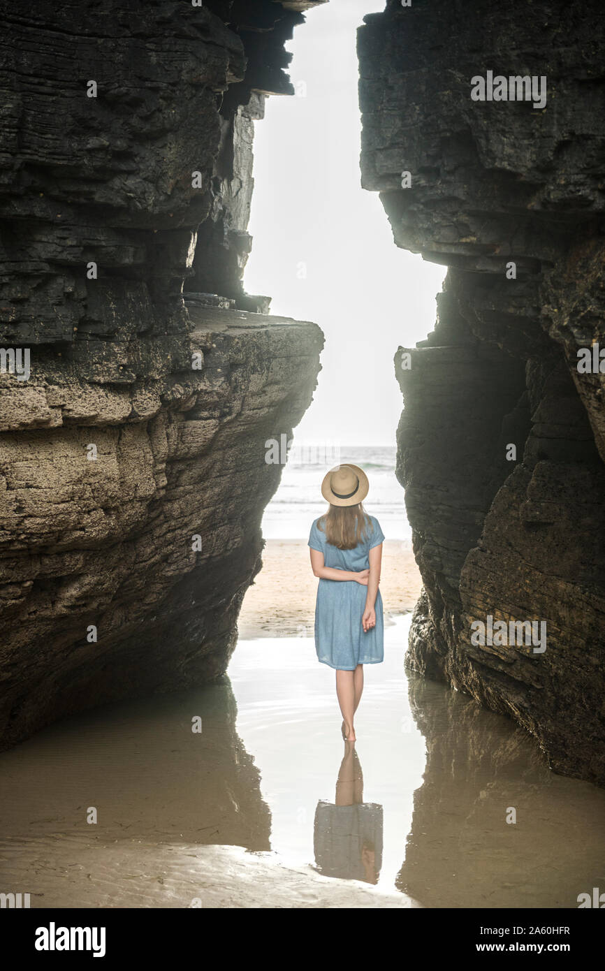 Femme debout sur la plage avec des roches, des Cathédrales Vue arrière, Galice, Espagne Banque D'Images