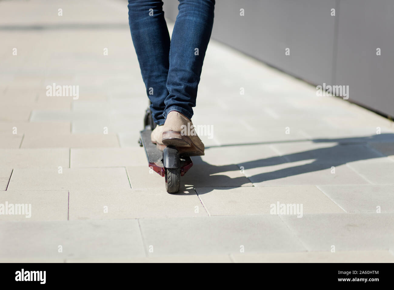 Les jambes de l'homme monté sur l'e-scooter dans la ville Banque D'Images