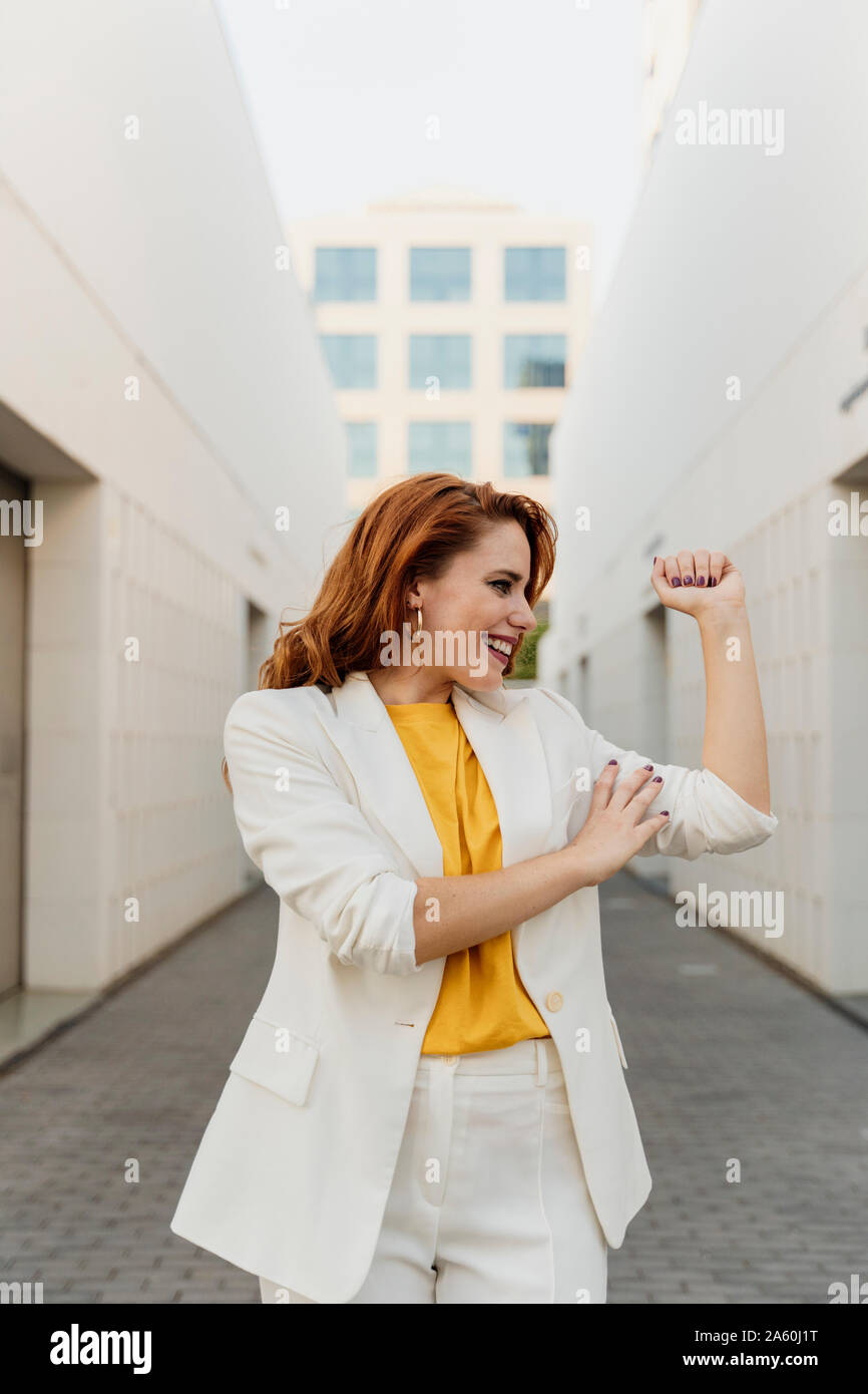 Femme énergique en costume pantalon blanc, fléchissant ses muscles Banque D'Images