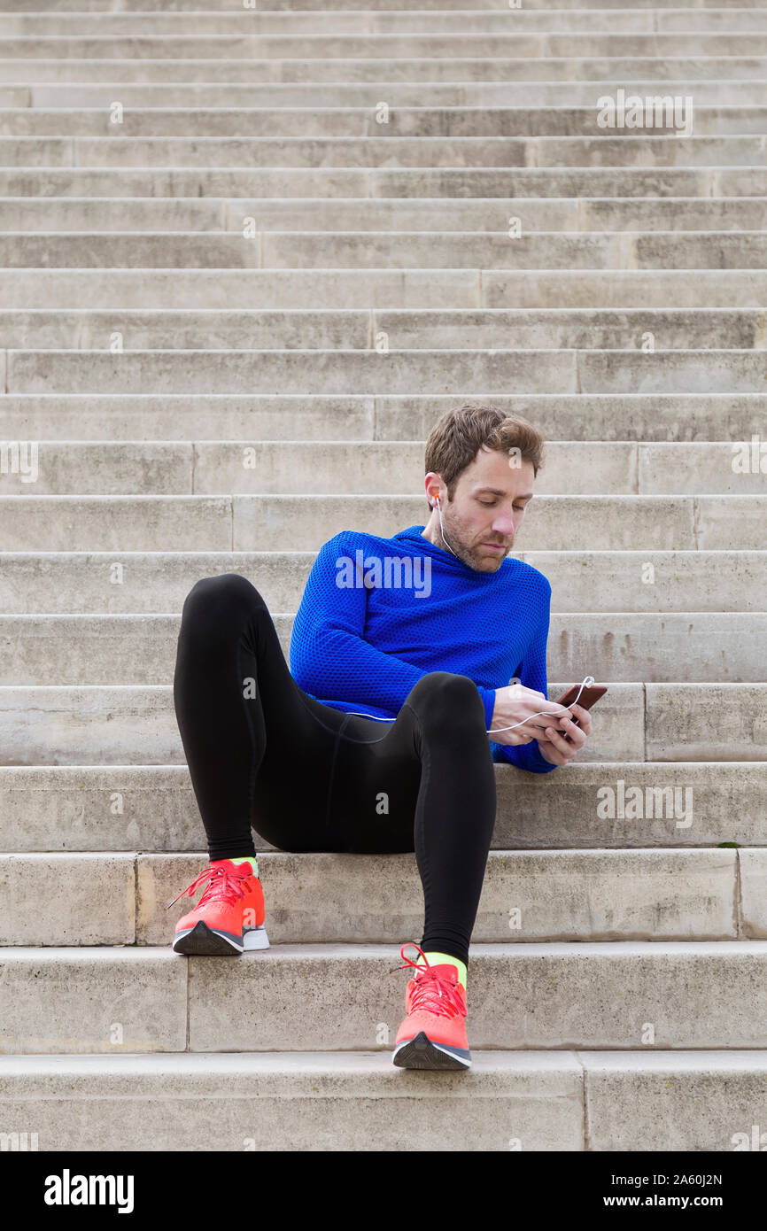 Jogger sitting on steps et using smartphone Banque D'Images