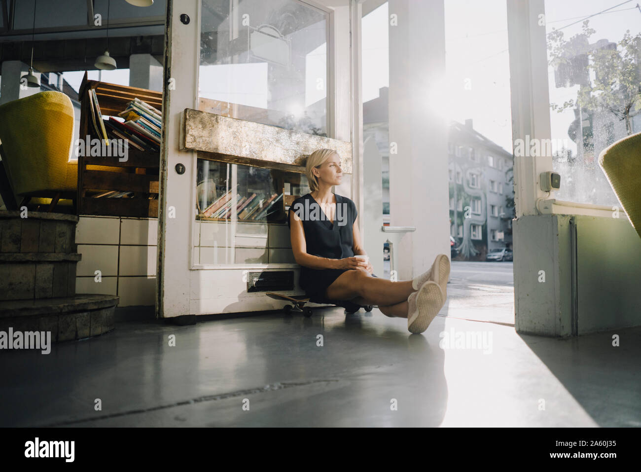 Businesswoman dans un café, assis sur planche, relaxant Banque D'Images