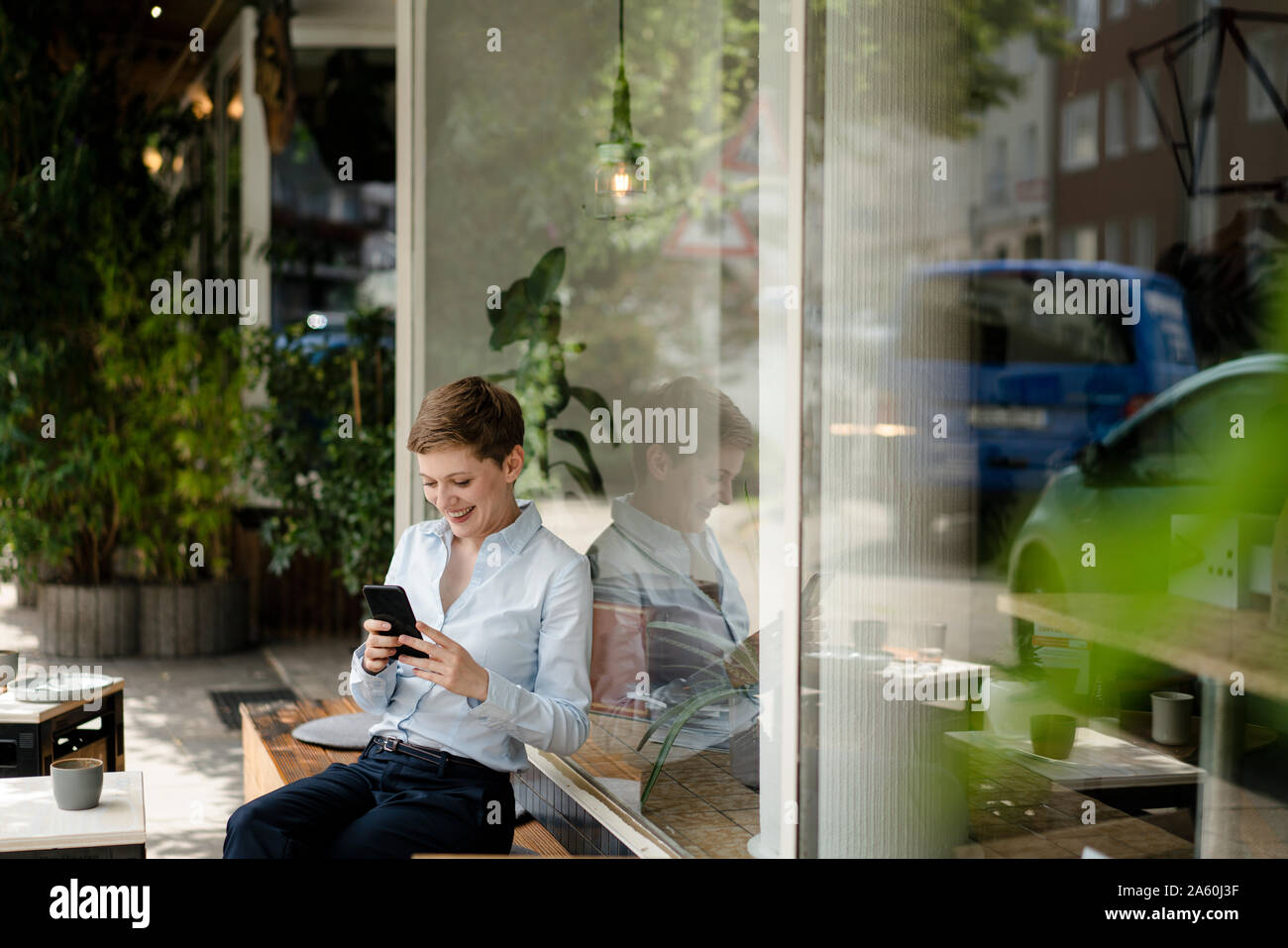 Businesswoman using cell phone at a cafe Banque D'Images
