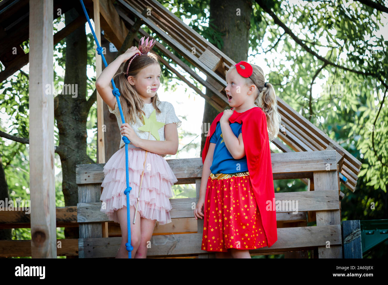 Les filles déguisée en princesse et superwoman jouant dans une maison d'arbre Banque D'Images