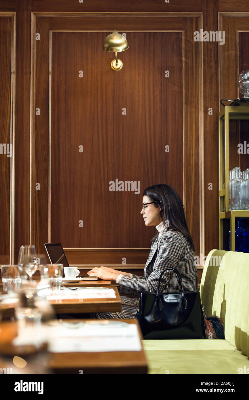 Businesswoman using laptop in a restaurant Banque D'Images