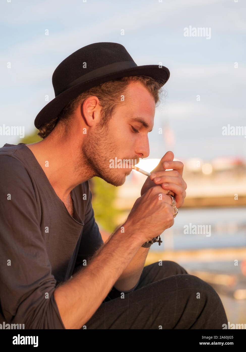 Jeune homme lors d'une fête, la cigarette d'éclairage Banque D'Images