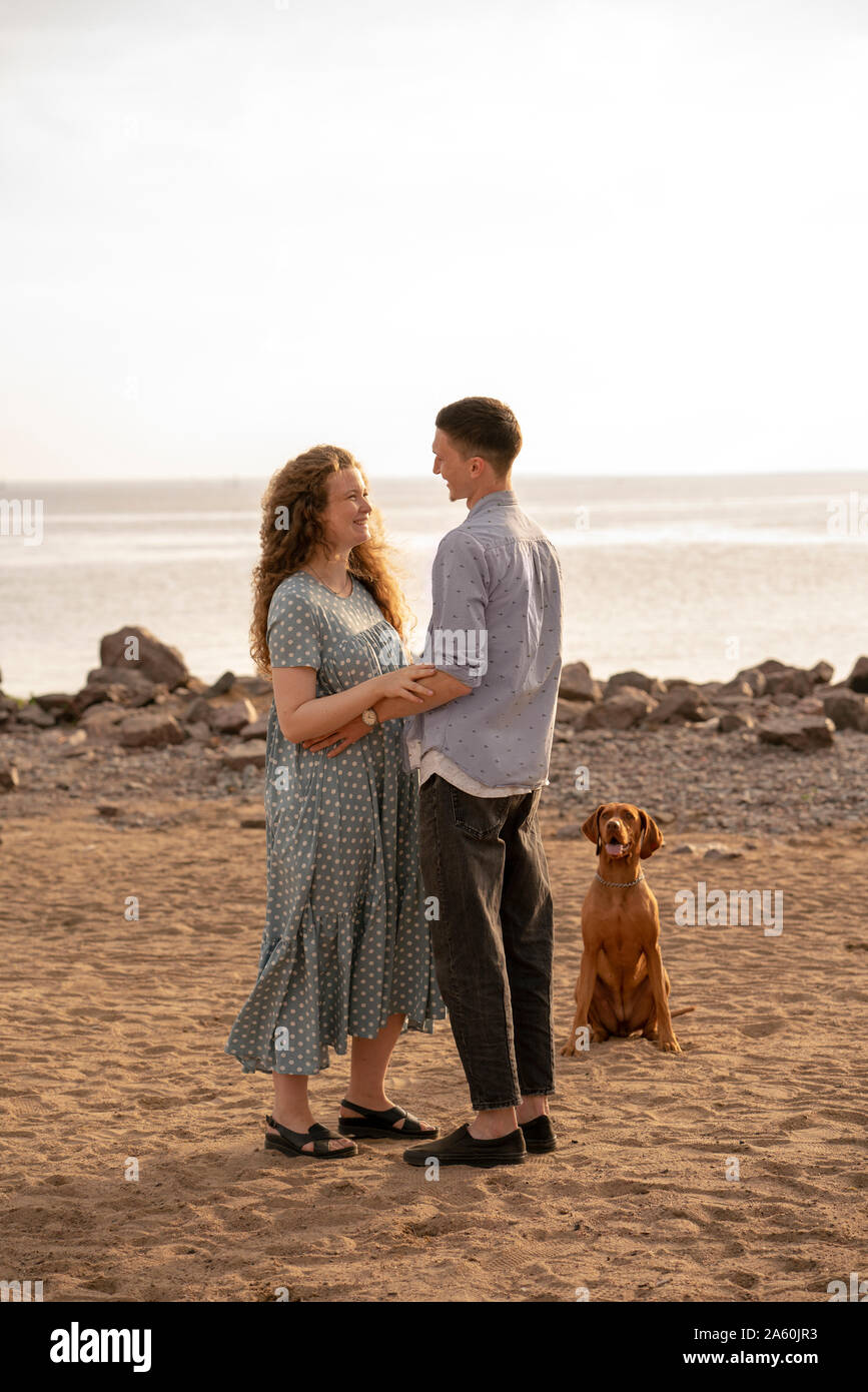 Jeune couple avec chien à la plage Banque D'Images