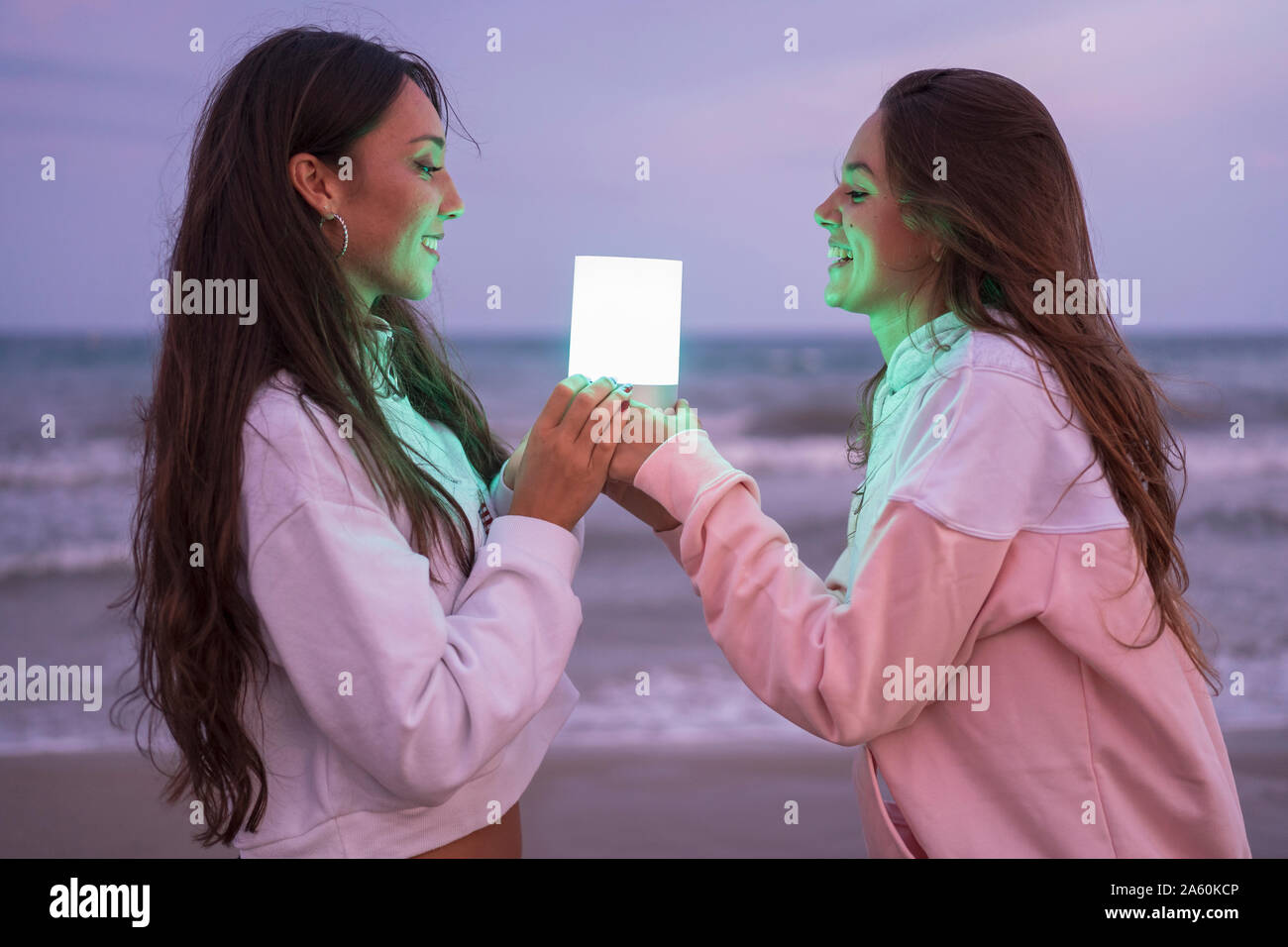 Deux happy female friends holding voyant sur la plage le soir Banque D'Images