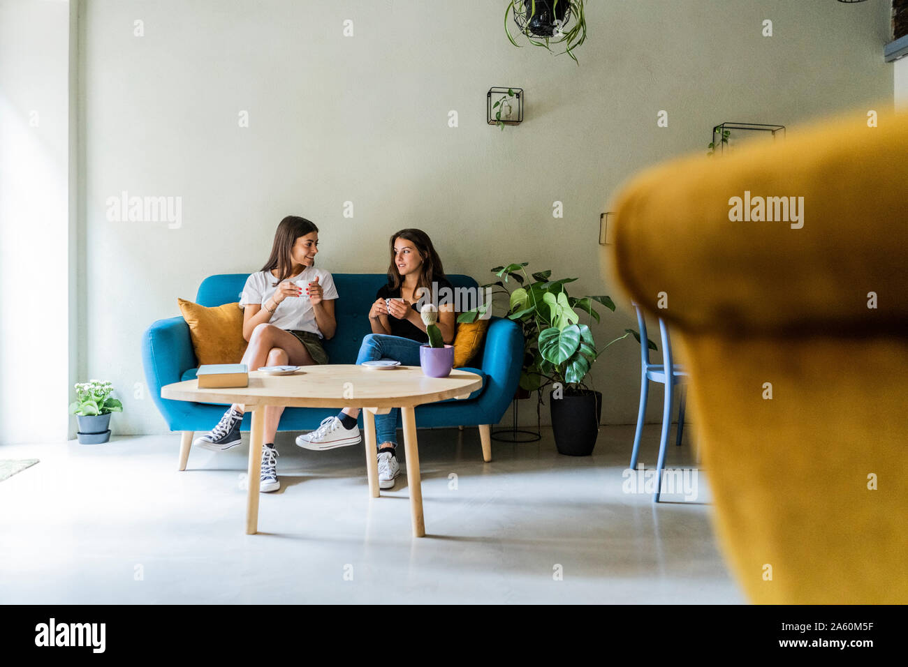 Deux jeunes amies, m'assis sur un canapé dans un café à parler Banque D'Images
