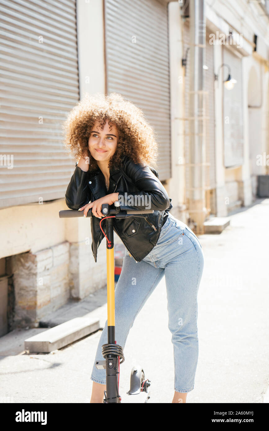 Portrait of smiling teenage girl with scooter sur la chaussée Banque D'Images