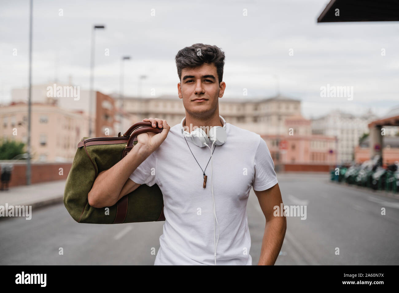 Jeune homme avec un sac à la gare portant des écouteurs Banque D'Images