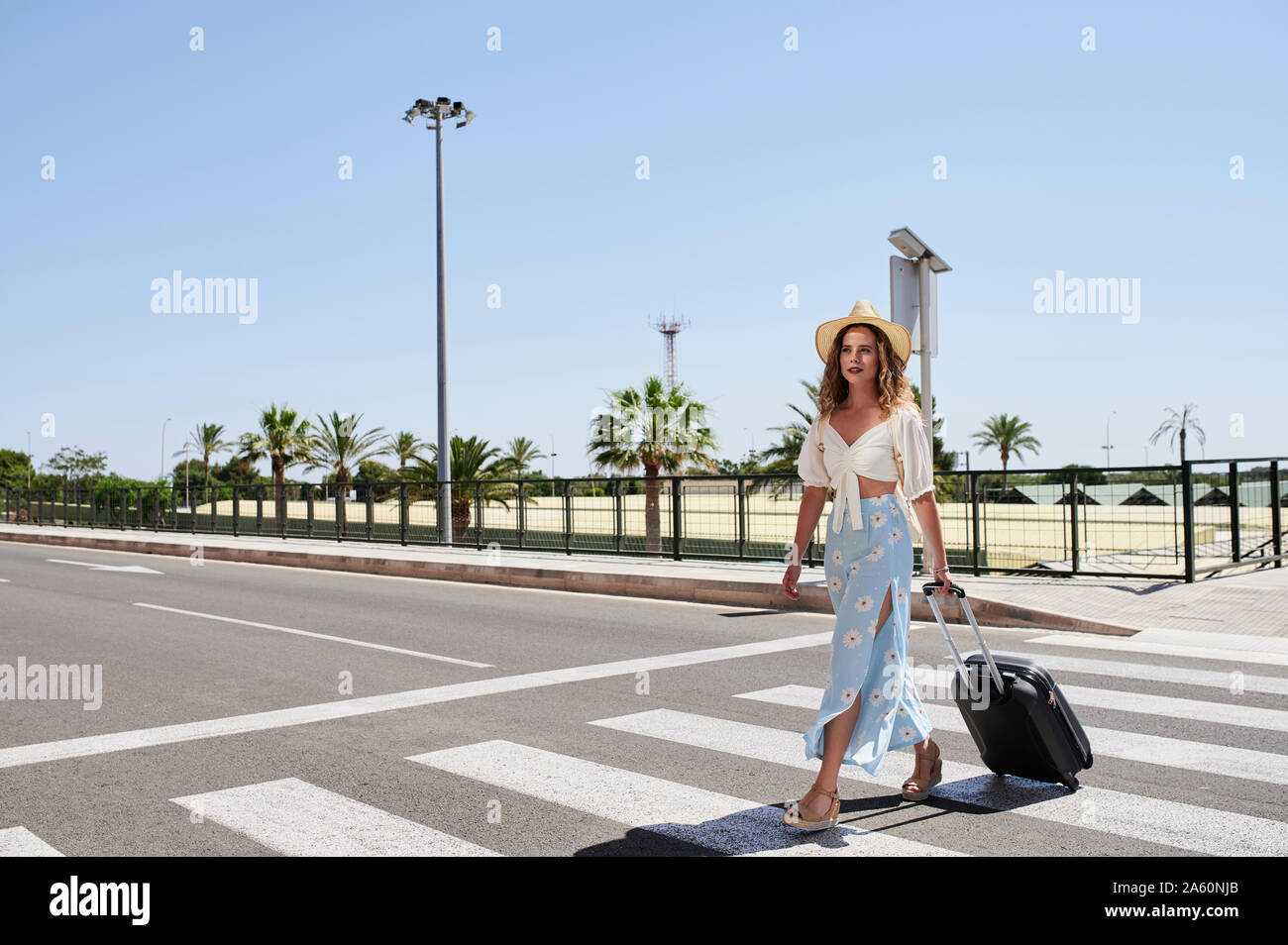 Jeune femme avec des bagages de traverser une rue à l'aéroport. Banque D'Images