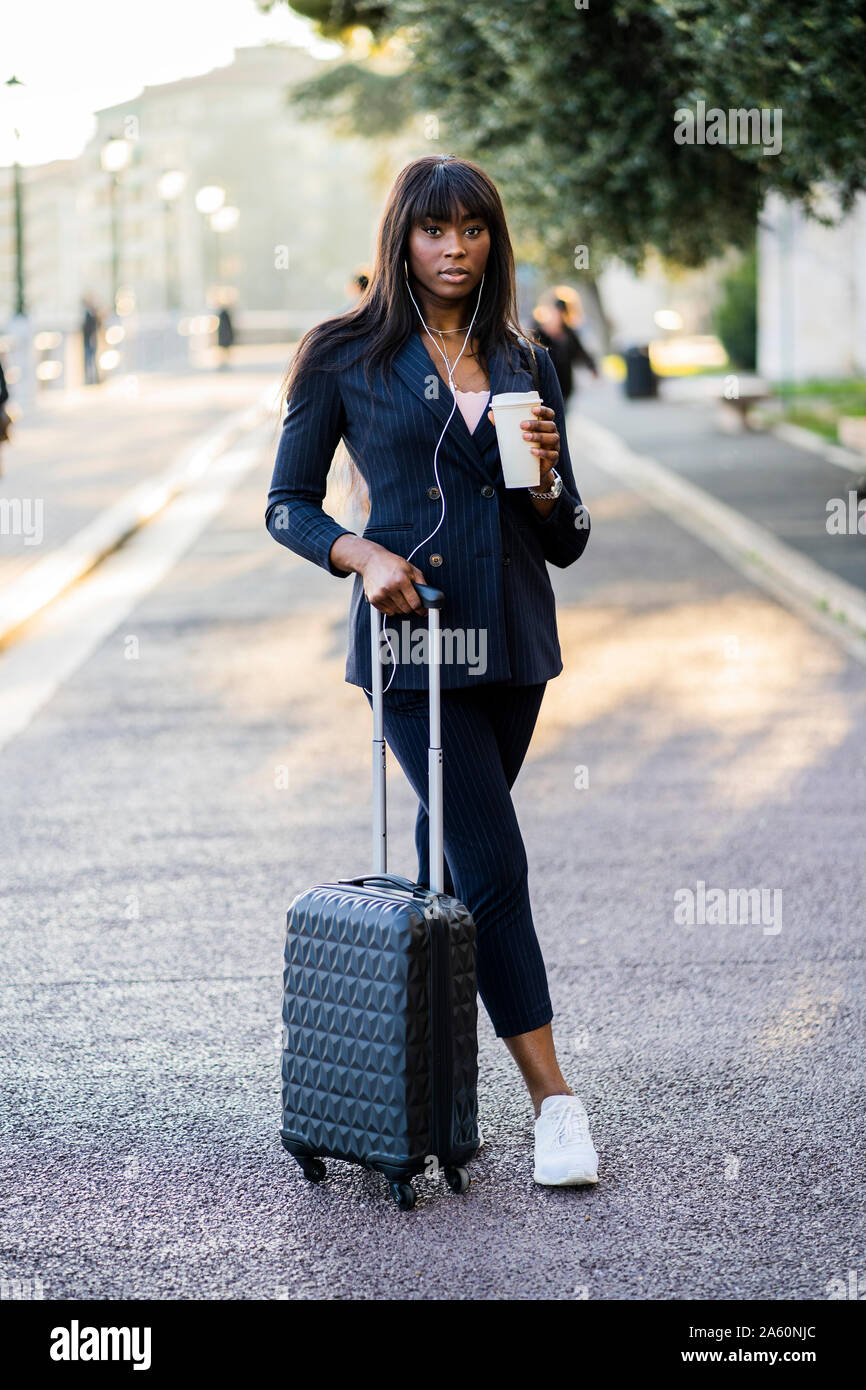 Portrait d'une femme avec valise et café à l'extérieur Banque D'Images