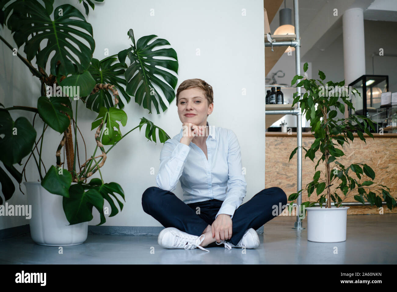 Portrait d'une femme assise sur le sol entouré de plantes Banque D'Images