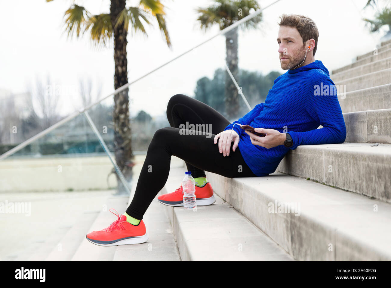 Jogger sitting on steps et using smartphone Banque D'Images