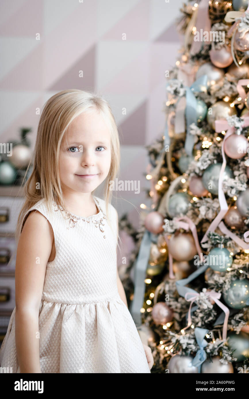 Portrait of smiling little Girl standing in front of lighted Christmas Tree Banque D'Images