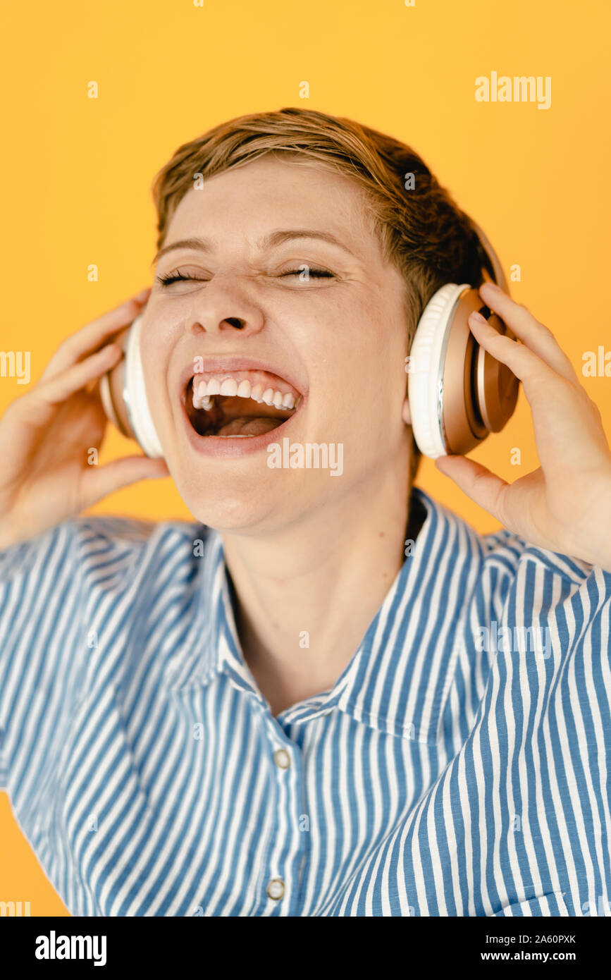 Portrait de carefree woman listening to music avec fond orange Banque D'Images