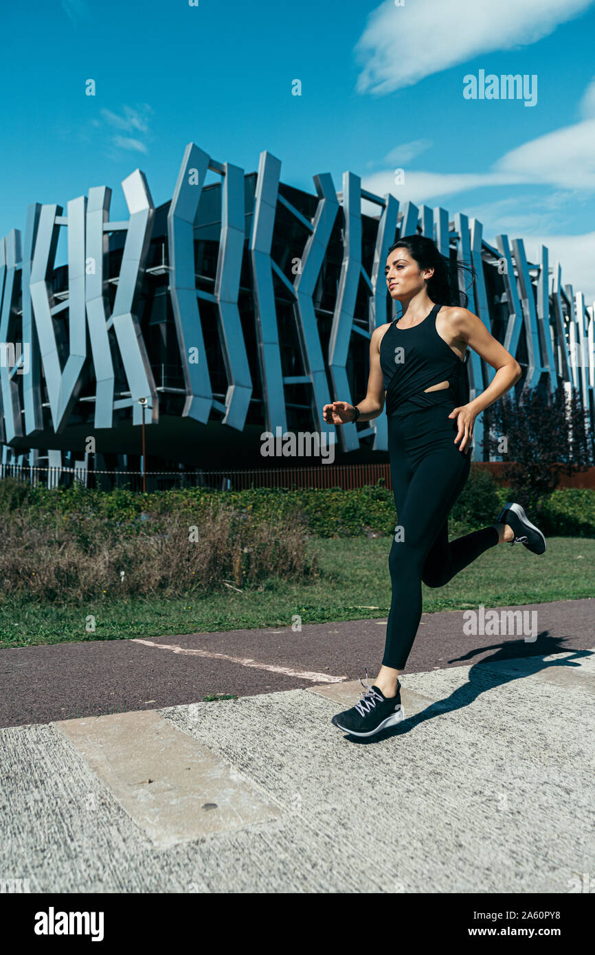 Jeune femme sur un chemin de jogging, un bâtiment moderne dans l'arrière-plan Banque D'Images