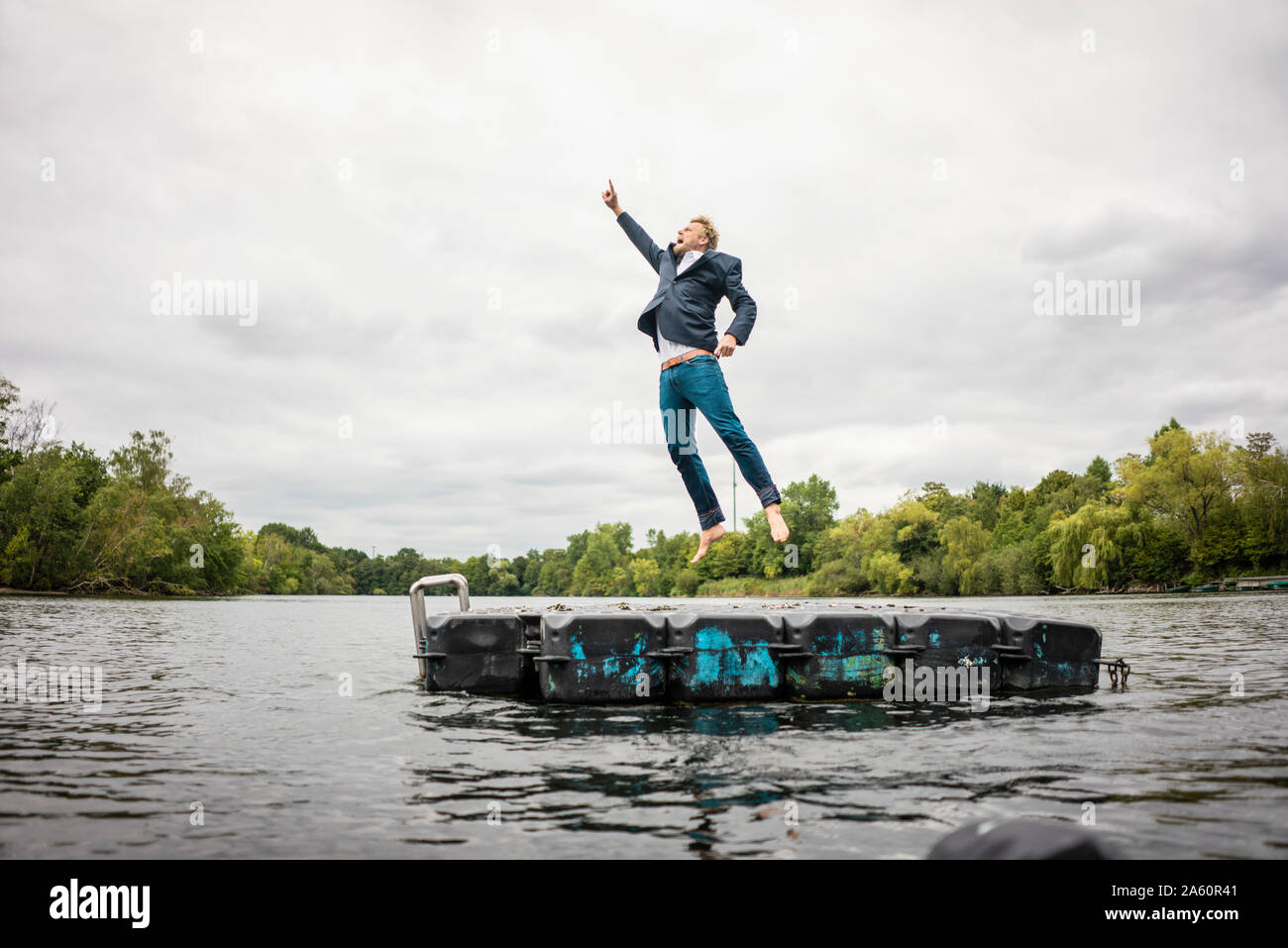 Businessman jumping sur plate-forme dans un lac Banque D'Images