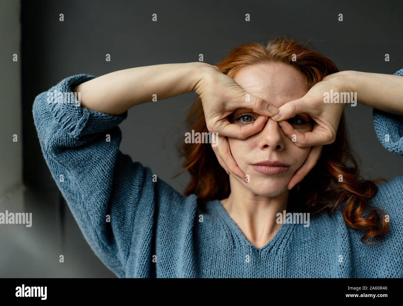 Portrait de femme rousse de l'élaboration de verres avec les doigts Banque D'Images