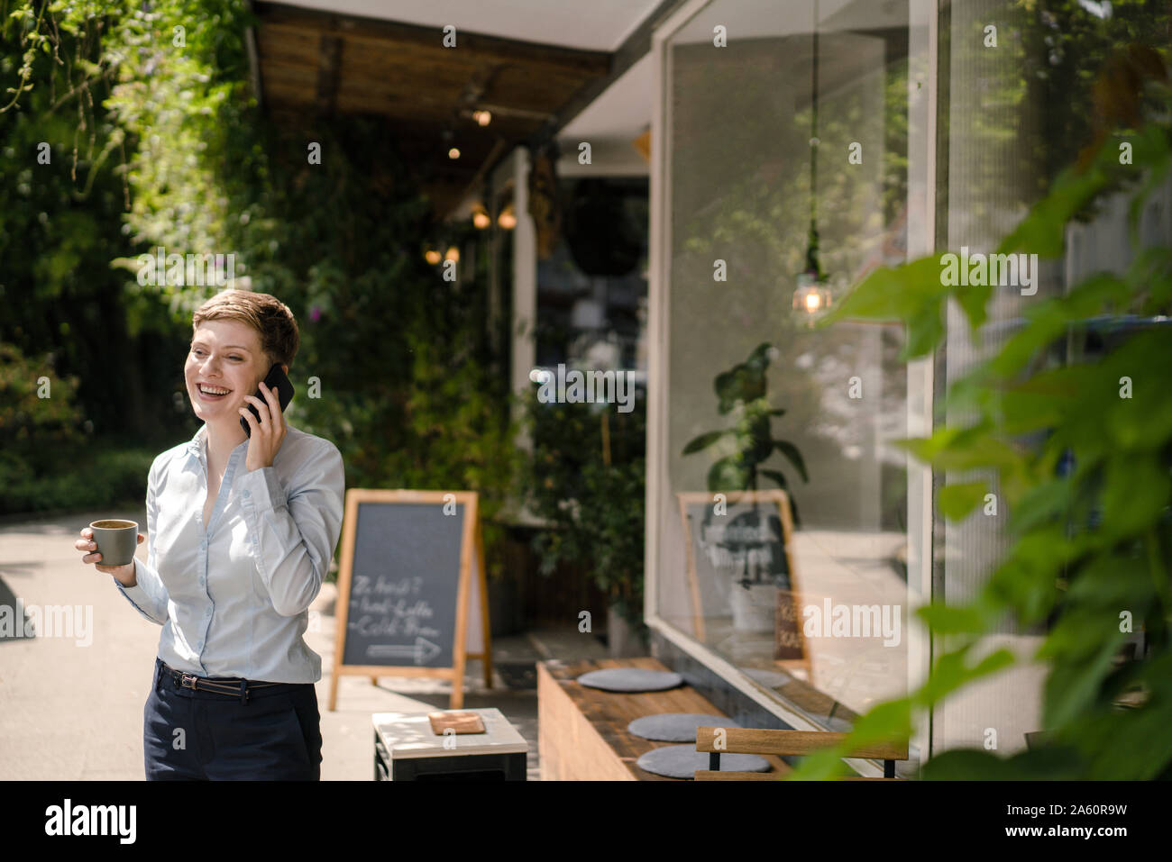 Happy businesswoman using cell phone at a cafe Banque D'Images