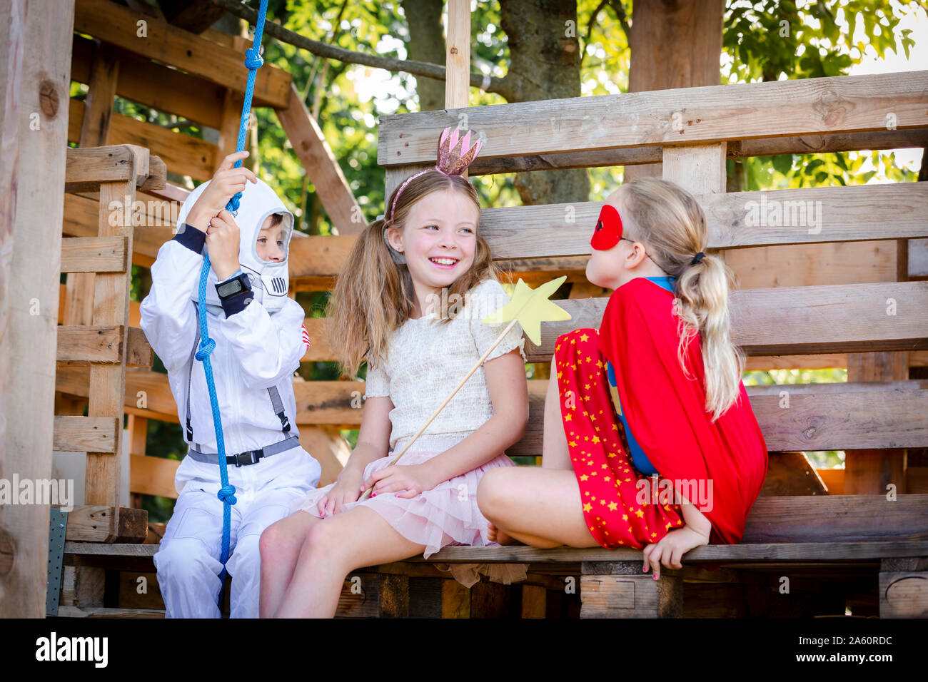 Trois enfants avec des costumes de super-héros jouant sur leur maison de l'arbre Banque D'Images