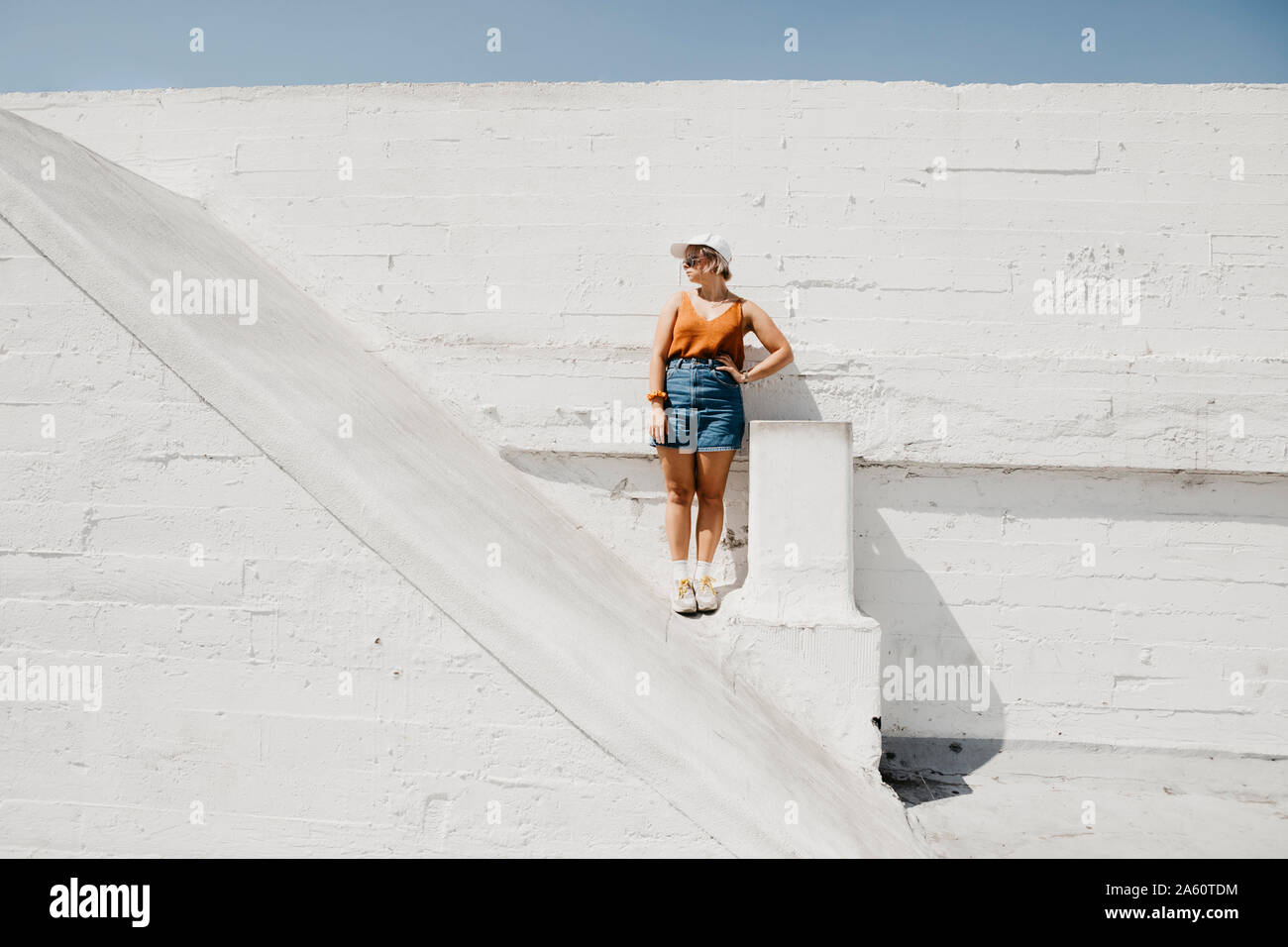 Jeune femme debout devant un mur blanc à l'extérieur Banque D'Images