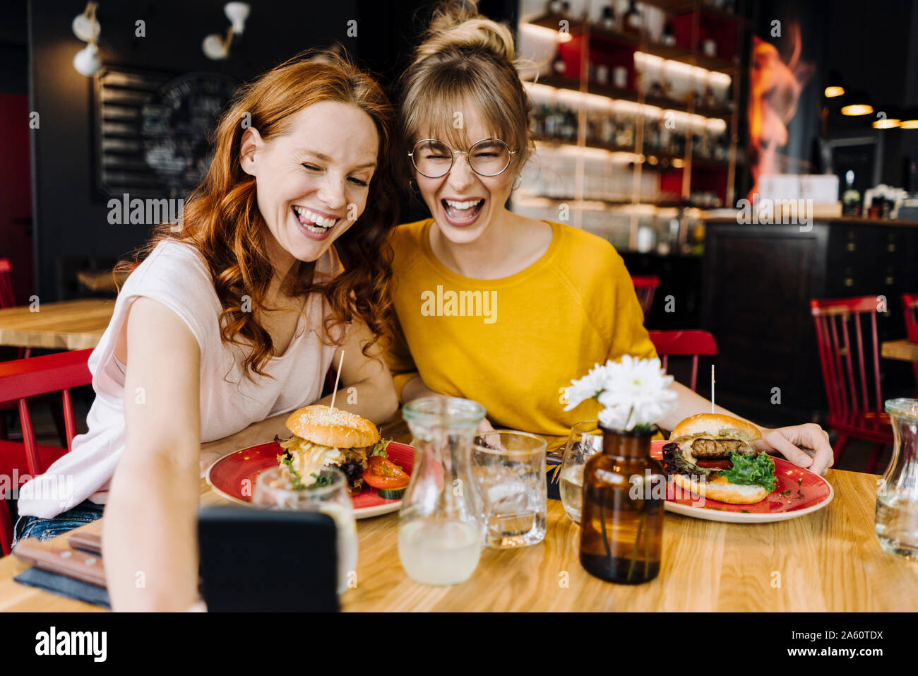 Deux heureux amis féminins ayant burger et prendre un dans un restaurant selfies Banque D'Images