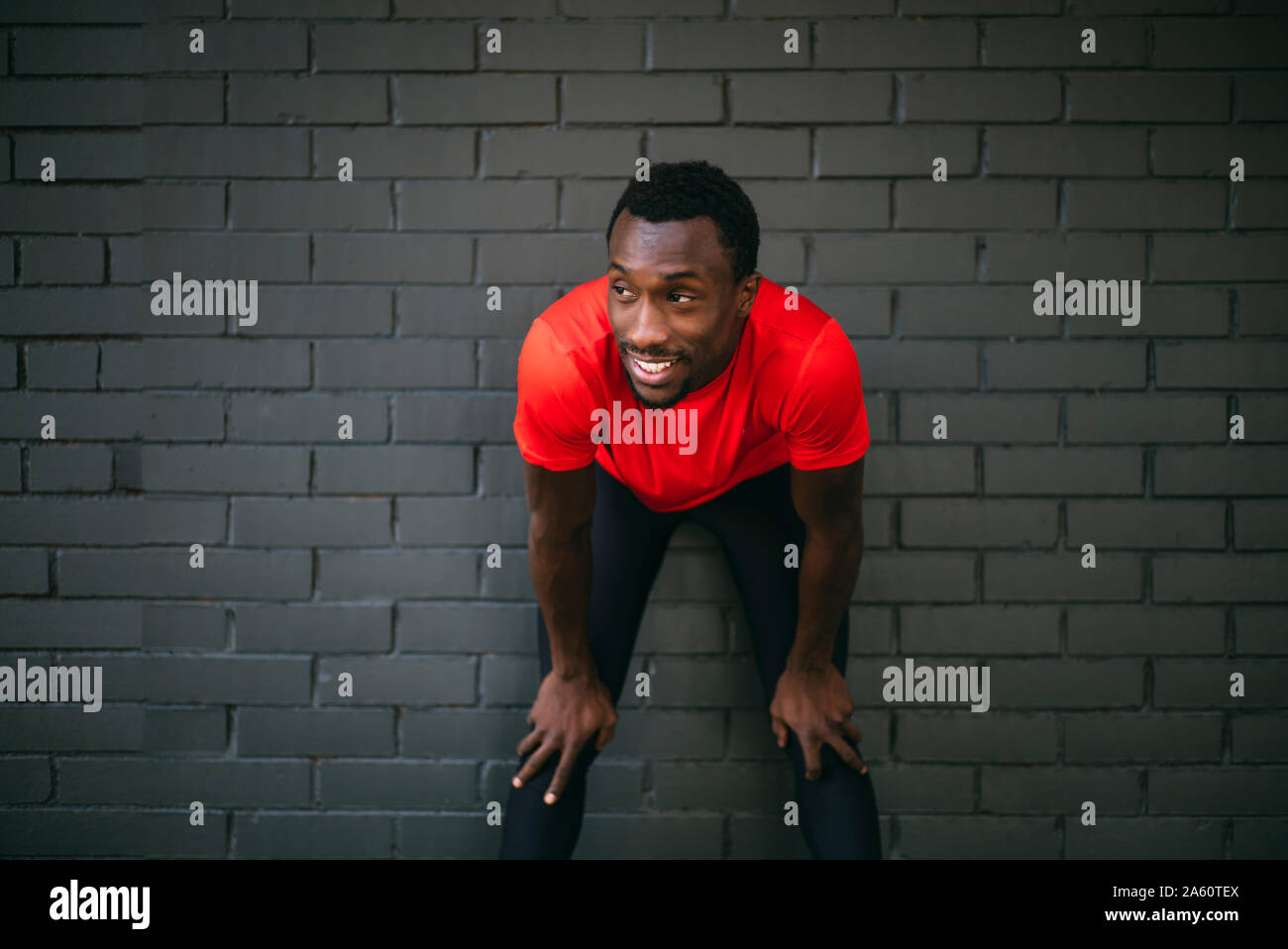 Jeune homme sportif de prendre une pause de la séance en face d'un mur de briques Banque D'Images