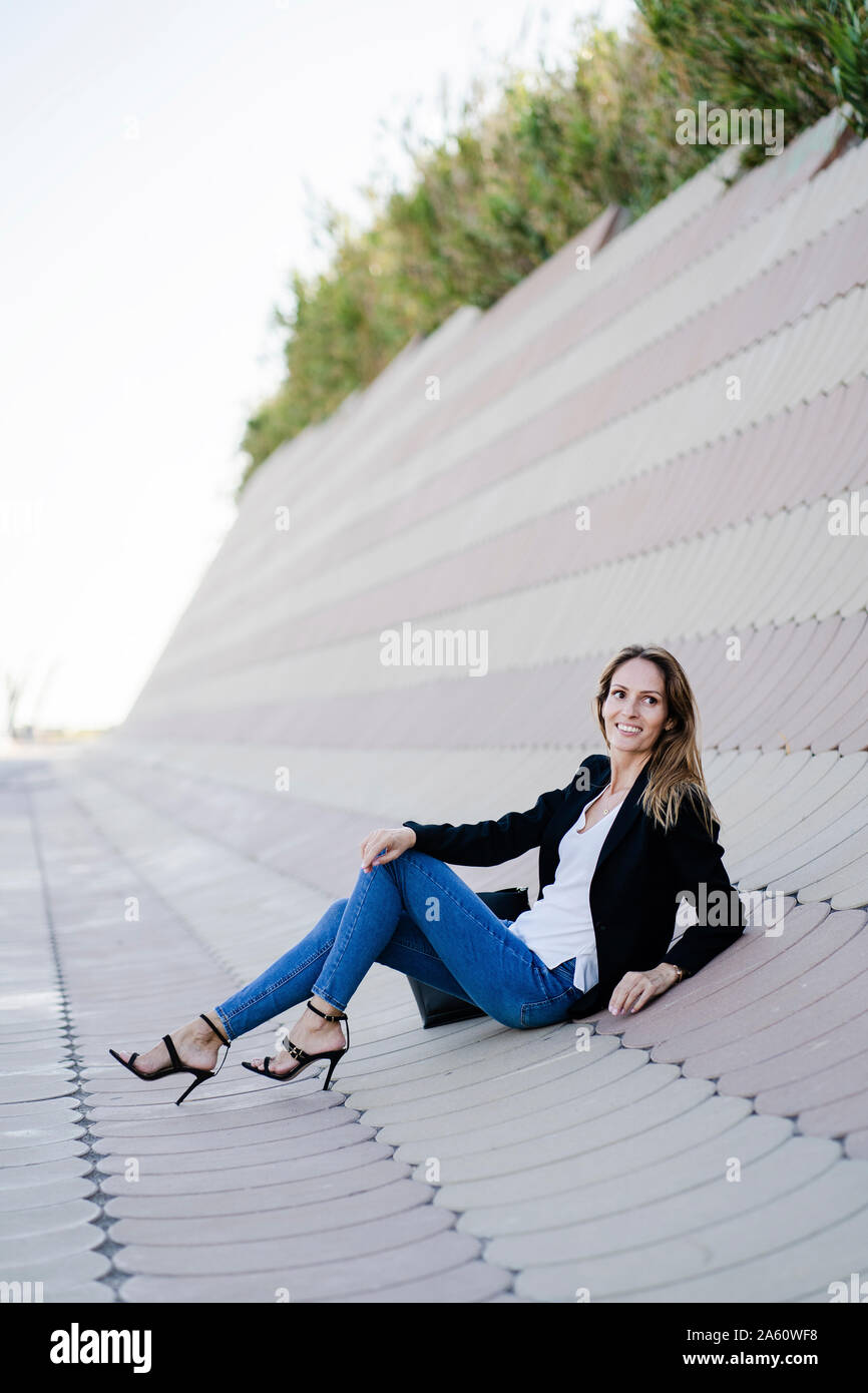 Businesswoman relaxing outdoors assis sur béton Banque D'Images