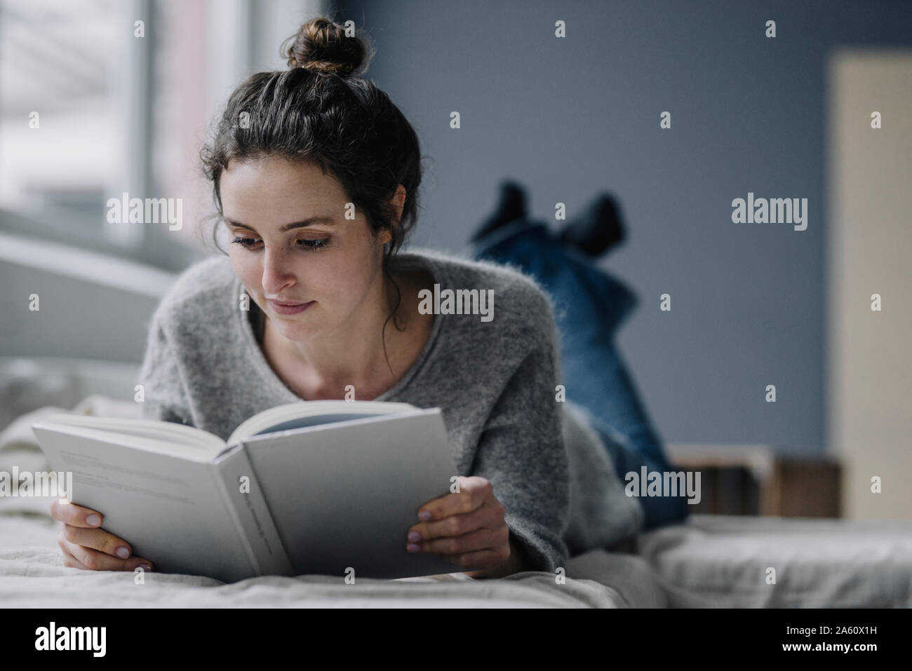 Portrait of young woman reading book at home Banque D'Images