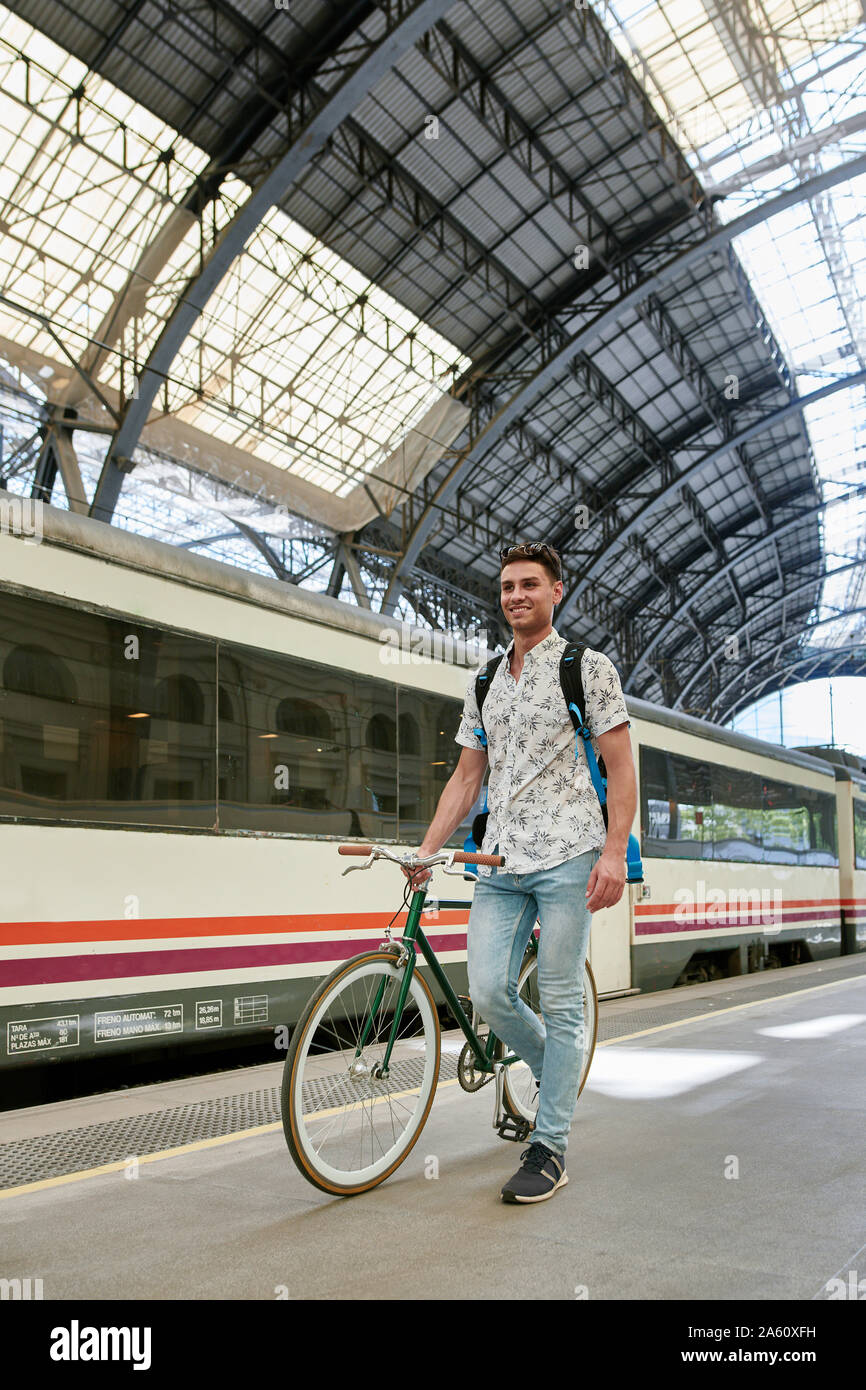 En poussant l'homme à vélo à travers une station Banque D'Images